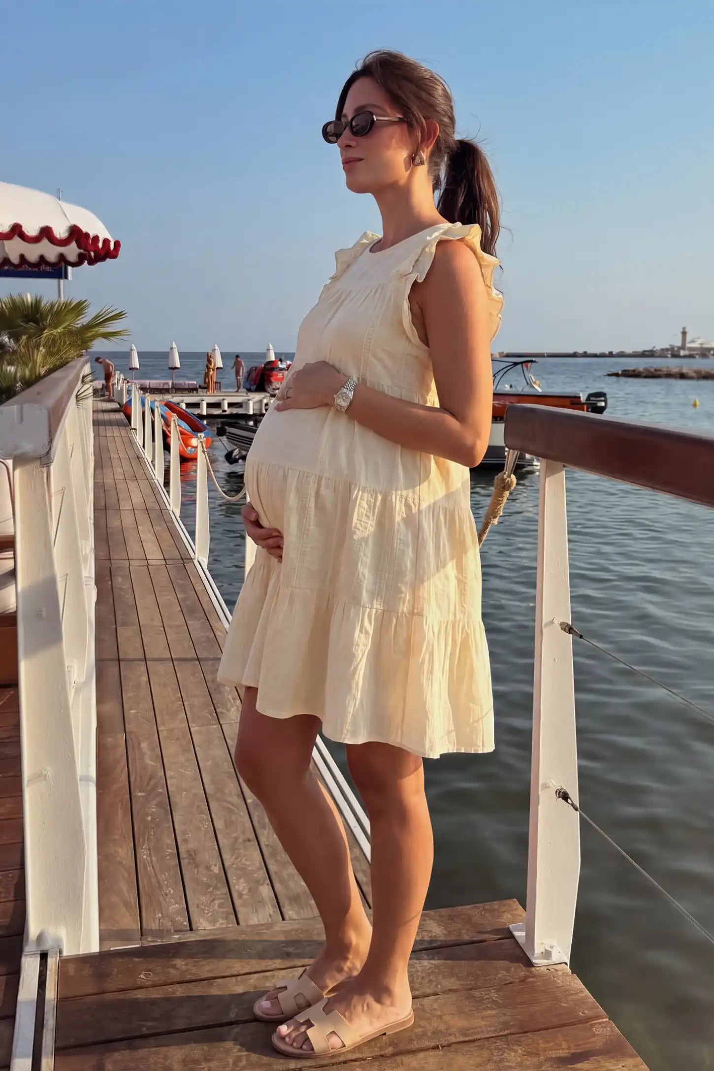 Crochet Detail Round Neck Tiered Maternity Short Dress Crochet detail round neck tiered maternity short dress in pale yellow with tiered & ruffle sleeve design, side view on pregnant model