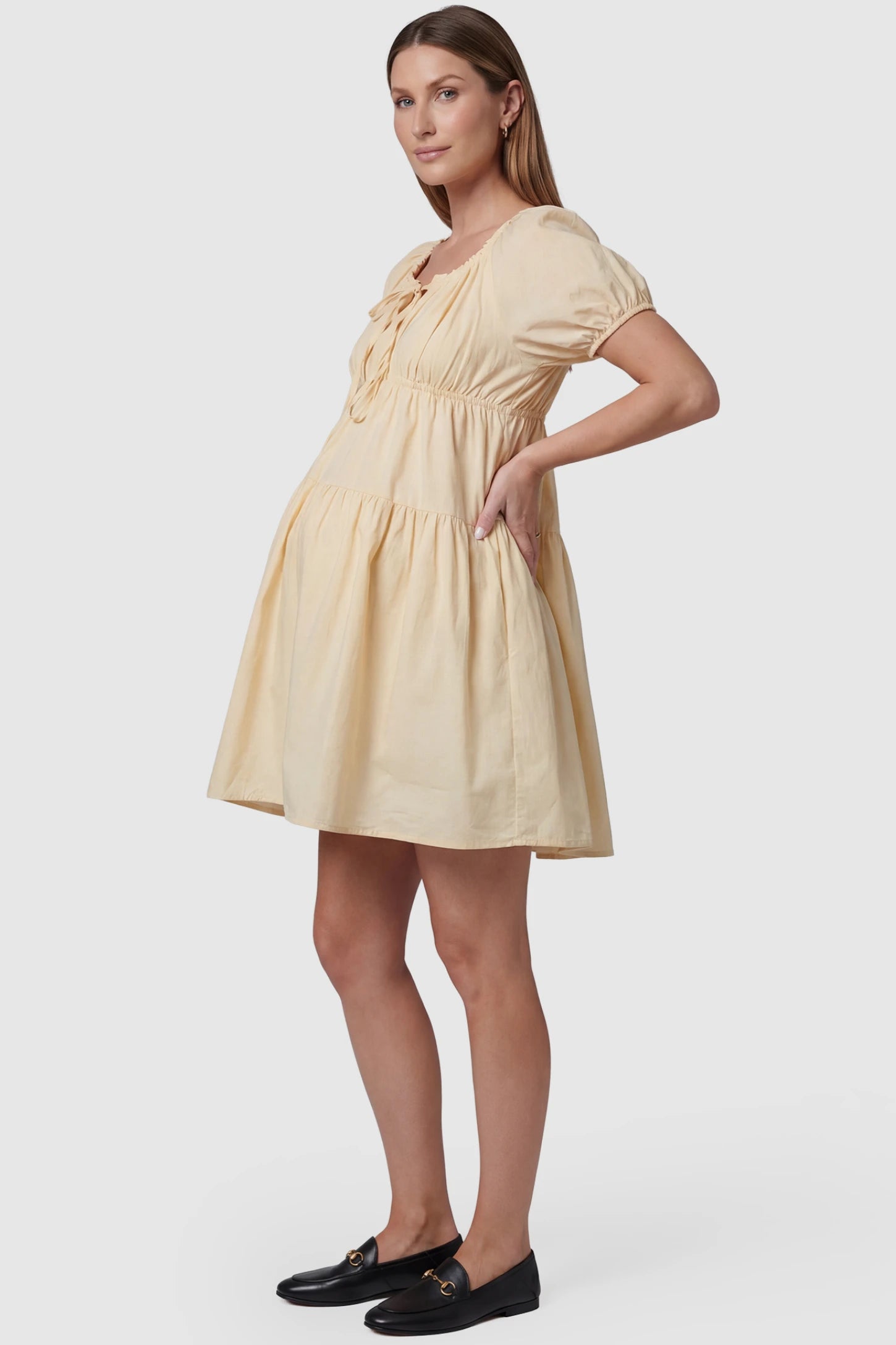 Short Sleeve Tiered A-Line Maternity Short Dress Short sleeve tiered A-line maternity short dress in yellow with elegant short sleeves, side view on pregnant model
