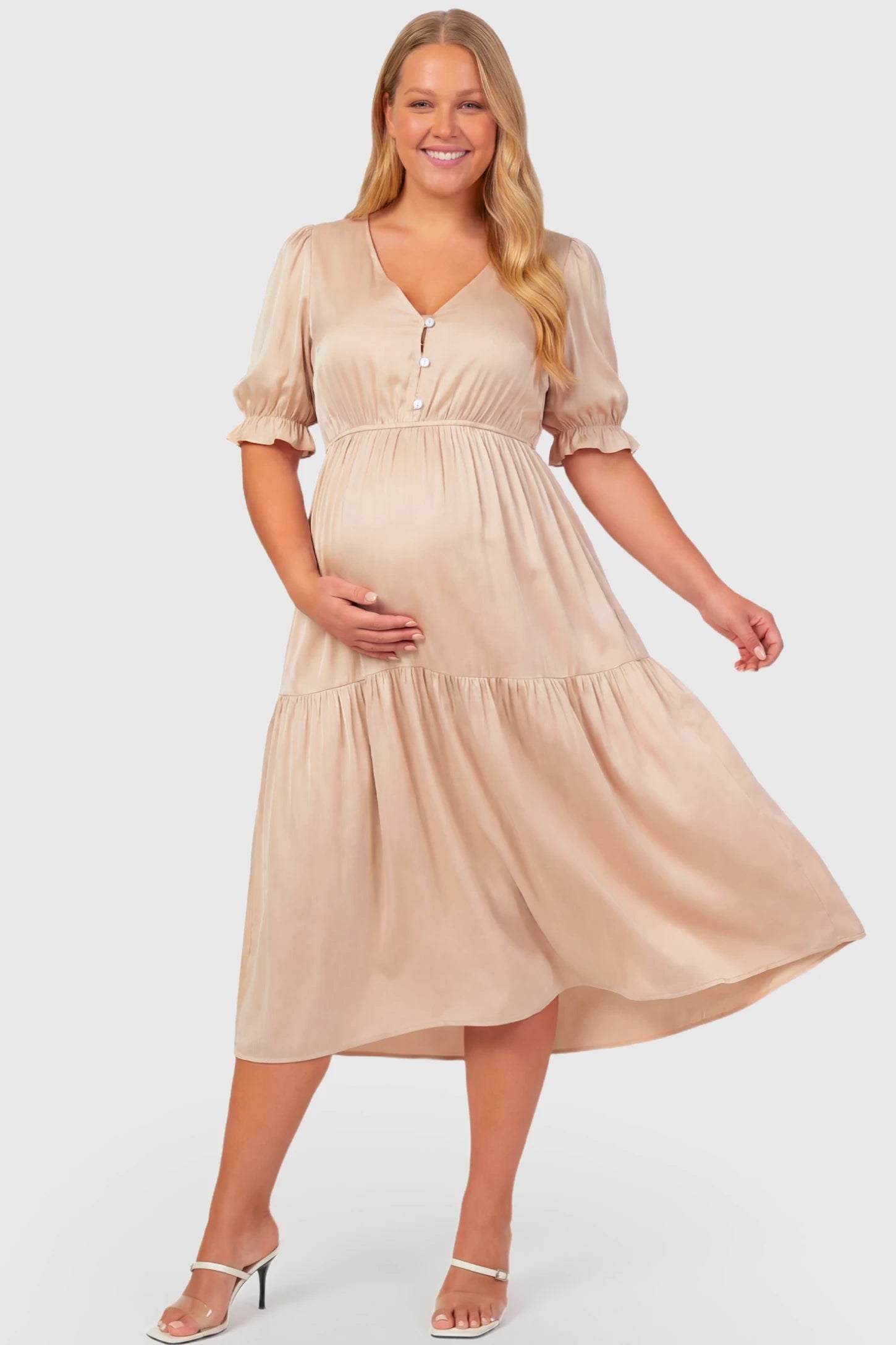 Tiered Hem A-Line Maternity Midi Dress Tiered Hem A-Line Maternity Midi Dress in apricot featuring empire waist, elbow-length puff sleeves, V-neckline, and flowy skirt on plus size pregnant model.