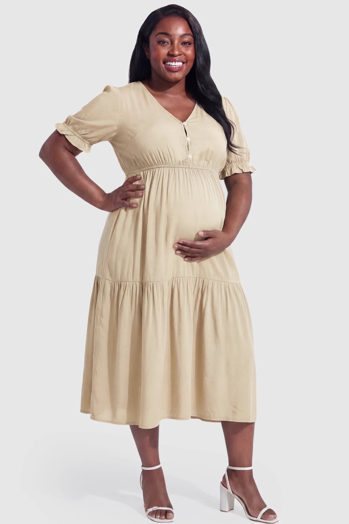 Tiered Hem A-Line Maternity Midi Dress Tiered Hem A-Line Maternity Midi Dress in apricot featuring empire waist, elbow-length puff sleeves, V-neckline, and flowy skirt on plus size pregnant model.