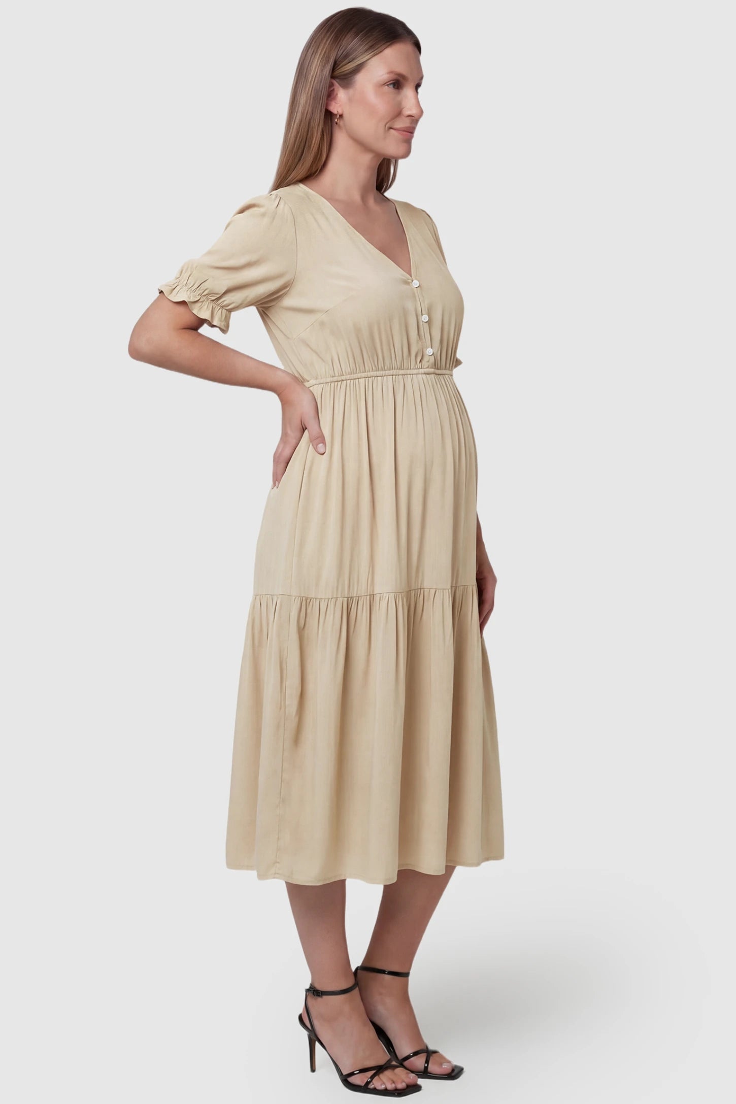 Tiered Hem A-Line Maternity Midi Dress Tiered Hem A-Line Maternity Midi Dress in apricot featuring empire waist, elbow-length puff sleeves, V-neckline, and flowy skirt on pregnant model. side view
