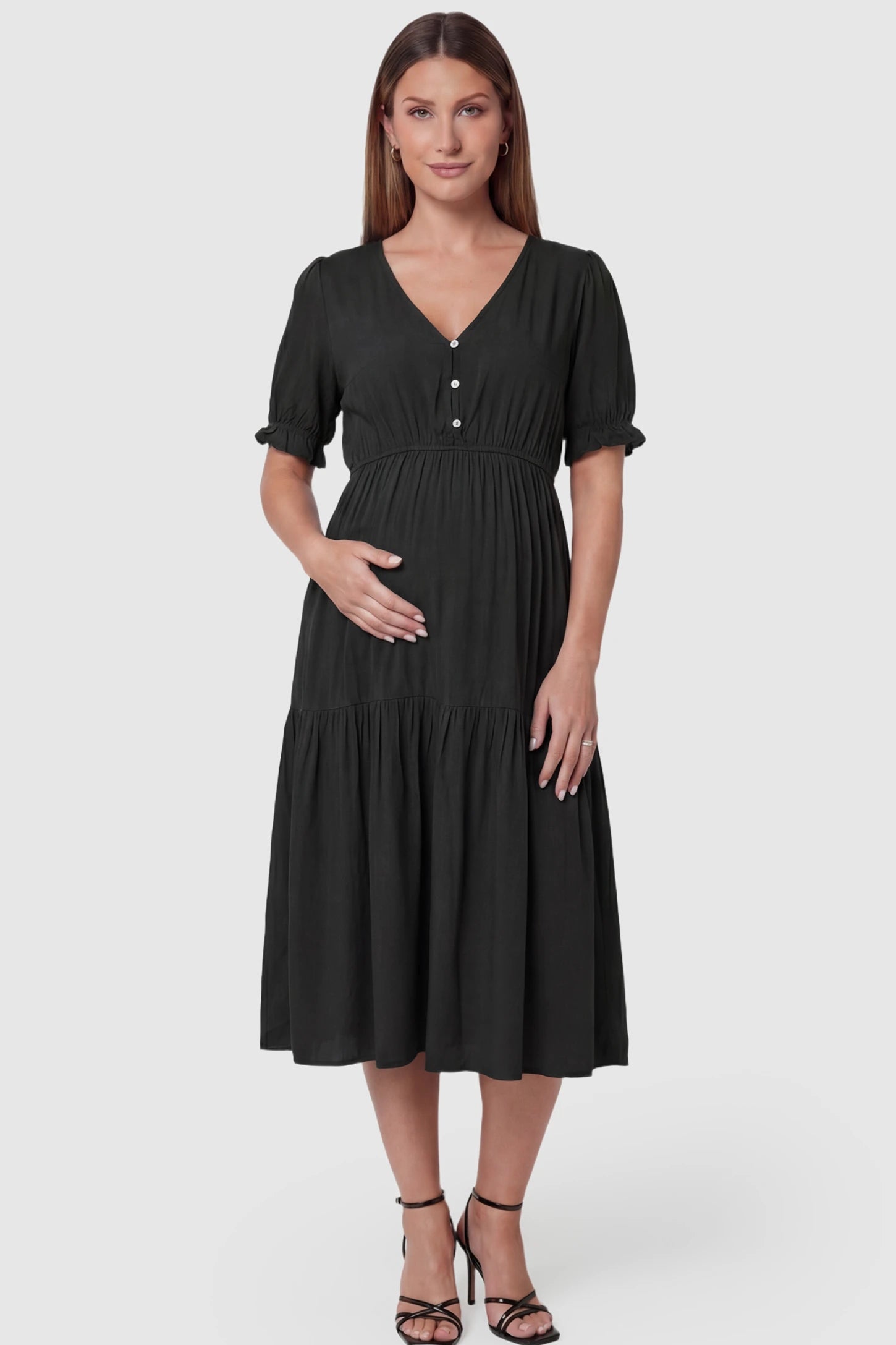 Tiered Hem A-Line Maternity Midi Dress  Tiered Hem A-Line Maternity Midi Dress in black featuring empire waist, elbow-length puff sleeves, V-neckline, and flowy skirt on pregnant model. front view