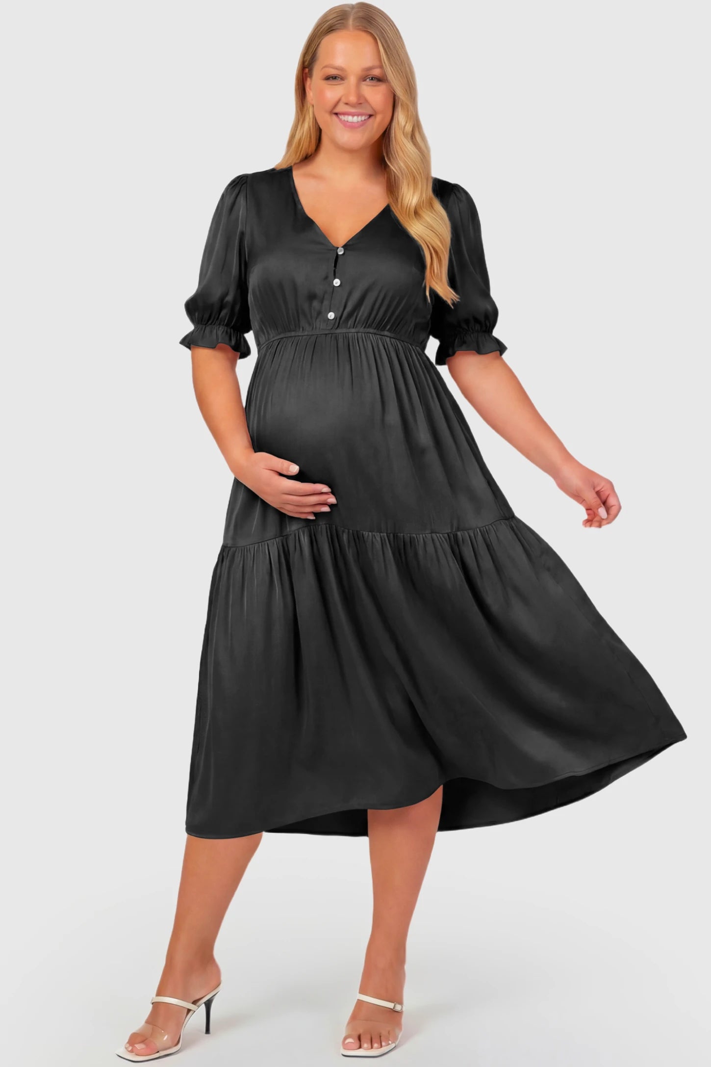 Tiered Hem A-Line Maternity Midi Dress Tiered Hem A-Line Maternity Midi Dress in apricot featuring empire waist, elbow-length puff sleeves, V-neckline, and flowy skirt on plus size pregnant model.