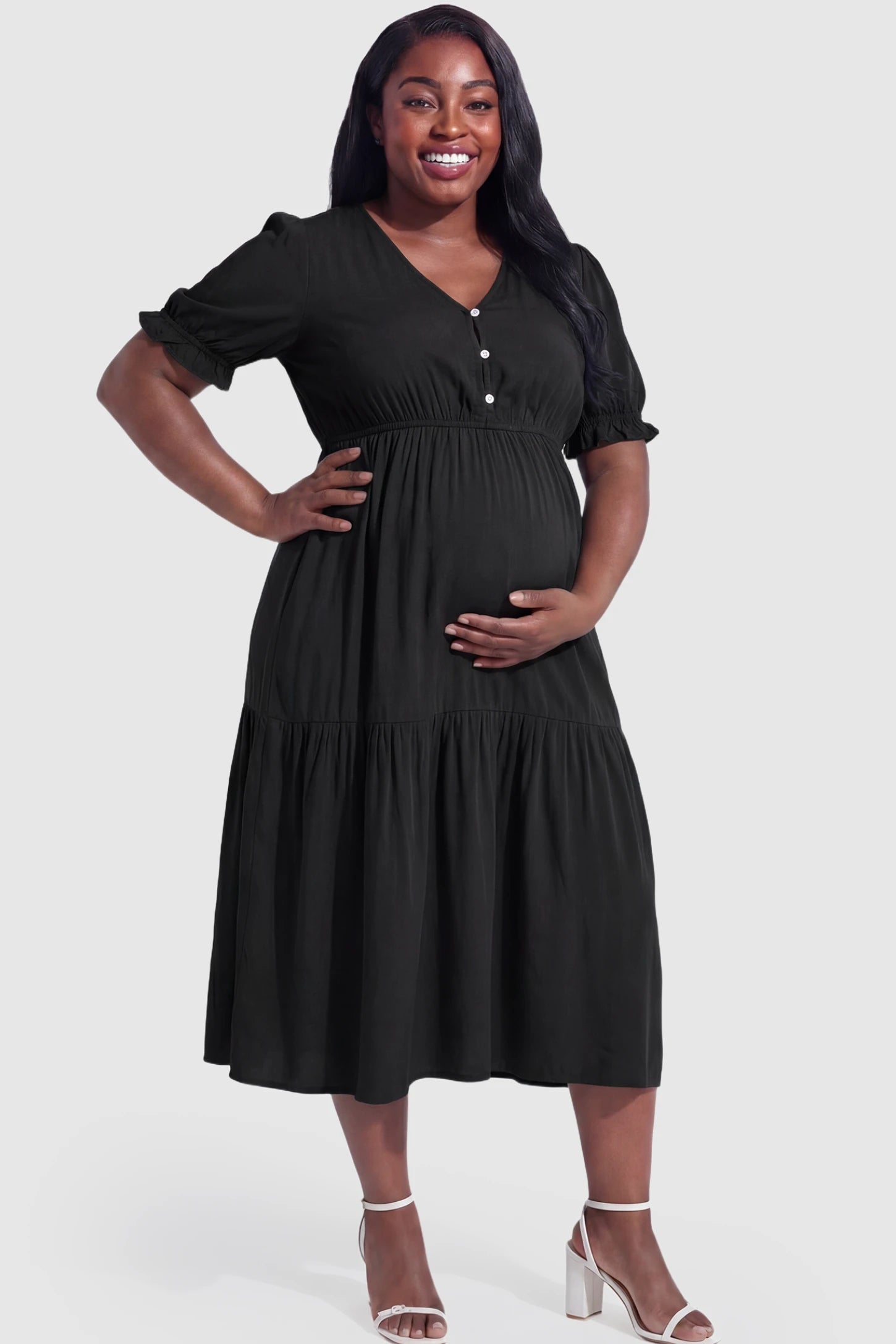 Tiered Hem A-Line Maternity Midi Dress  Tiered Hem A-Line Maternity Midi Dress in black featuring empire waist, elbow-length puff sleeves, V-neckline, and flowy skirt on plus size pregnant model.