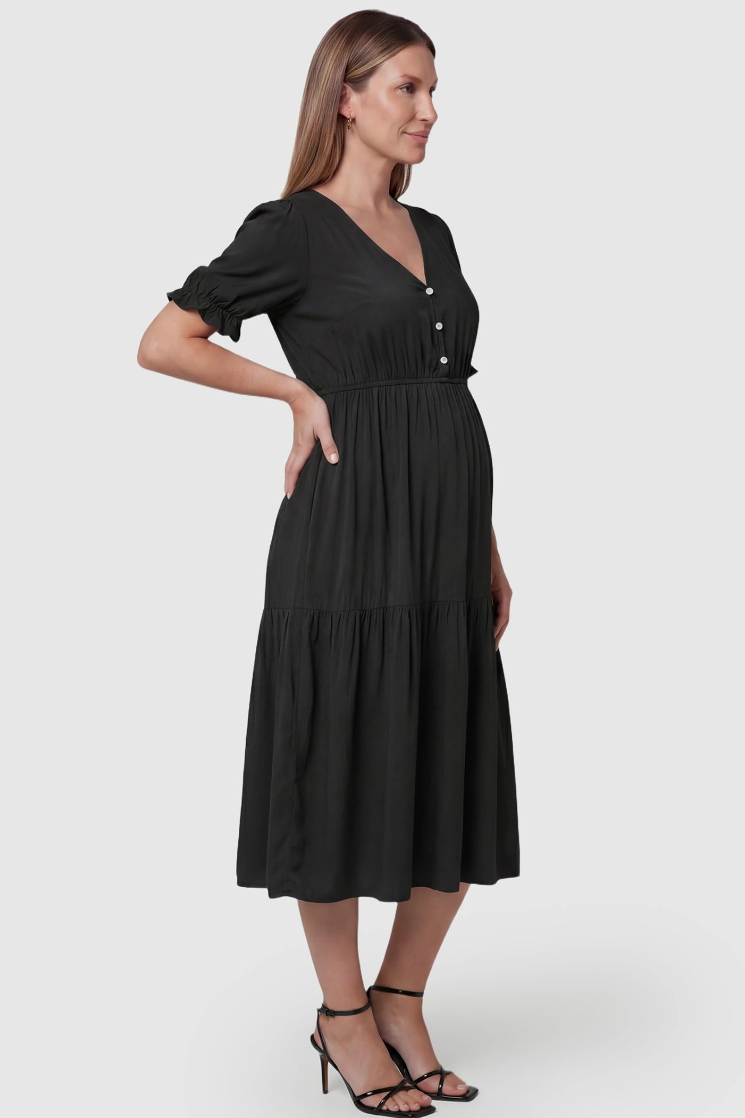 Tiered Hem A-Line Maternity Midi Dress  Tiered Hem A-Line Maternity Midi Dress in black featuring empire waist, elbow-length puff sleeves, V-neckline, and flowy skirt on pregnant model. side view