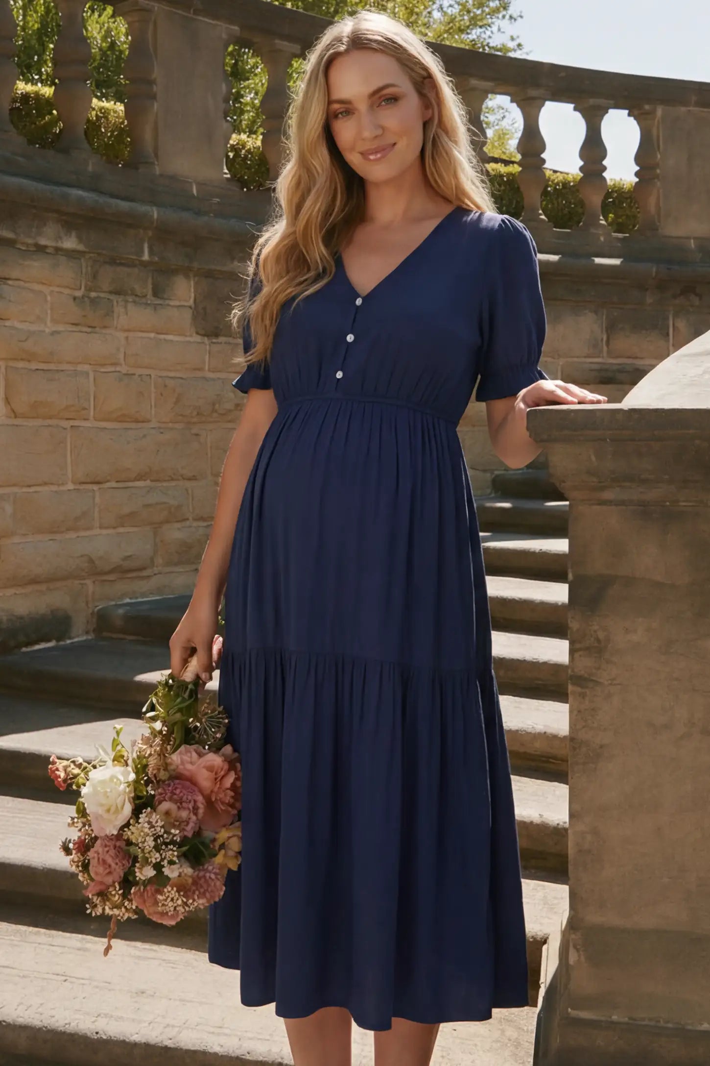 Tiered Hem A-Line Maternity Midi Dress  Tiered Hem A-Line Maternity Midi Dress in navy blue featuring empire waist, elbow-length puff sleeves, V-neckline, and flowy skirt on pregnant model.