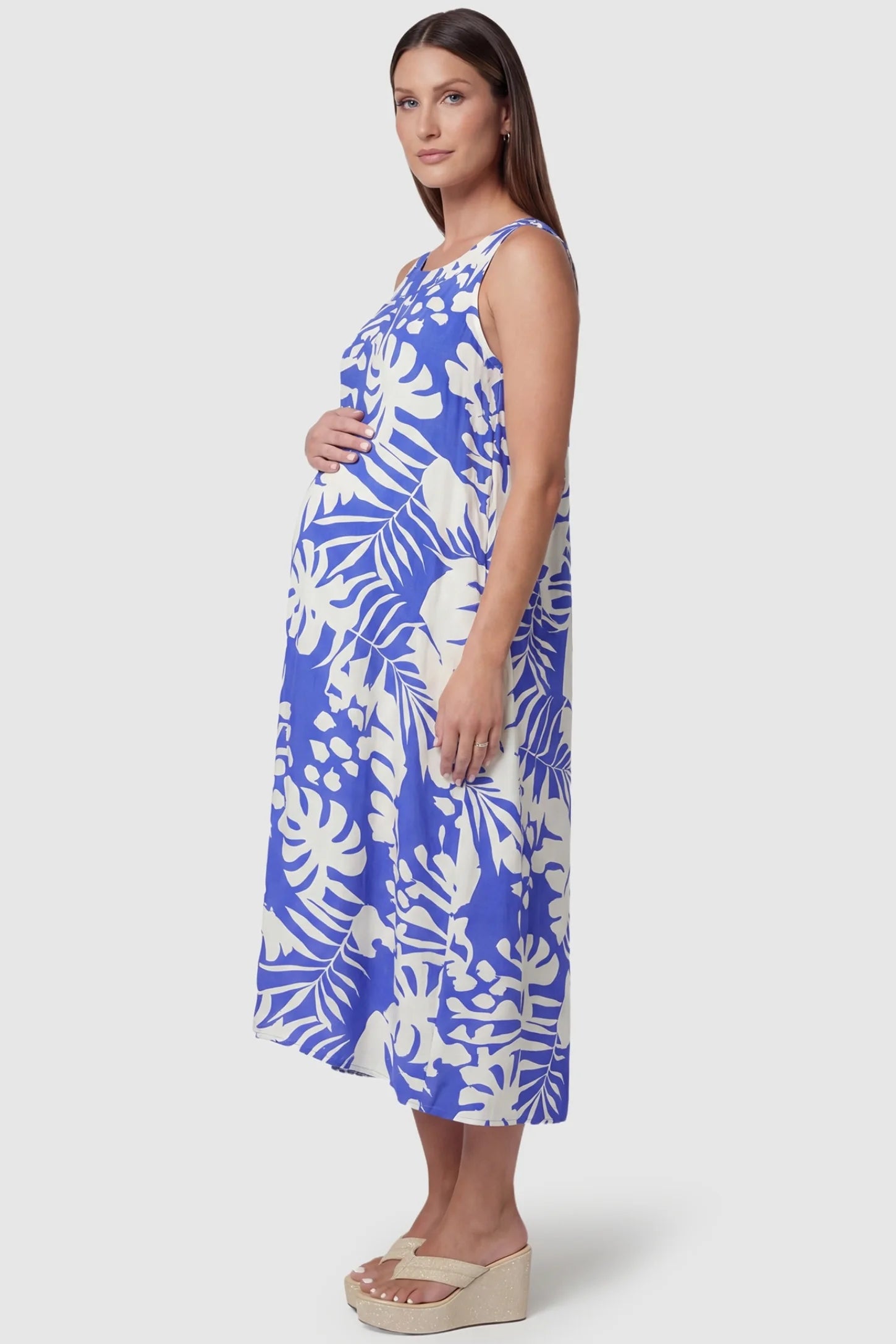 Tropical Print V-Back Sleeveless Midi Maternity Dress Side view of Blue Tropical Print V-Back Sleeveless Midi Maternity Dress featuring a flowy A-line cut on a pregnant model.