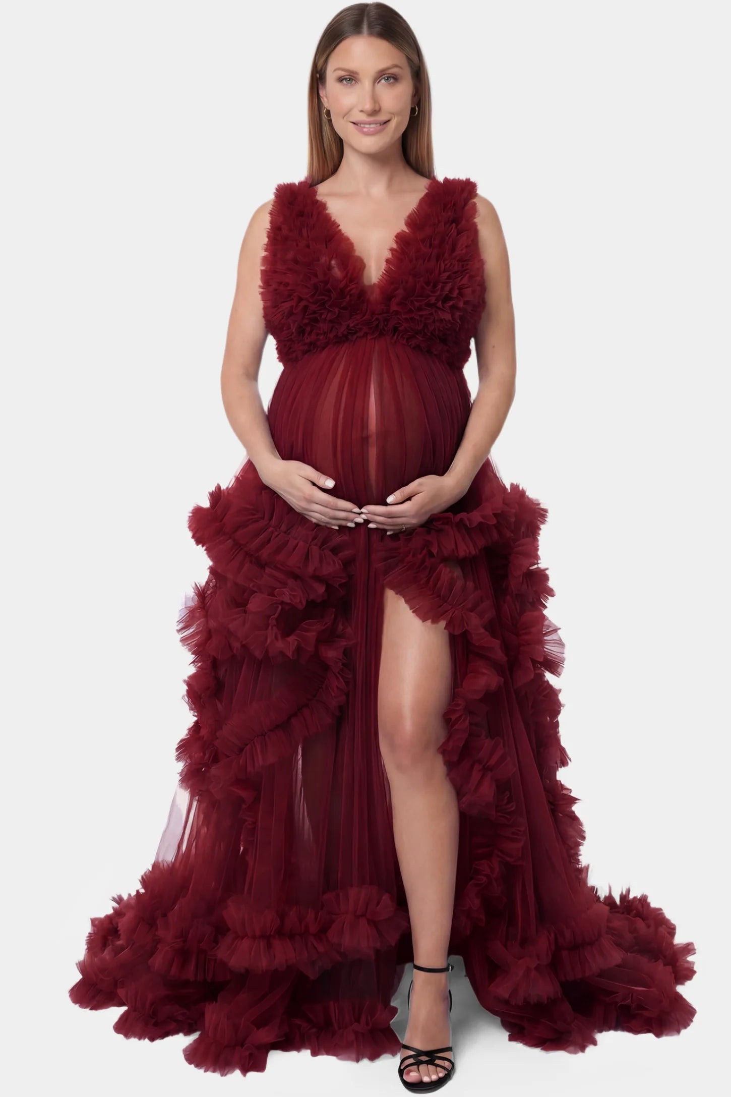 Multi-Layered Tulle Deep V-Neck Sleeveless Maxi Maternity Gown Multi-layered tulle deep V-neck sleeveless maxi maternity gown in burgundy featuring flowing pleated silhouette in full body front view on a pregnant model