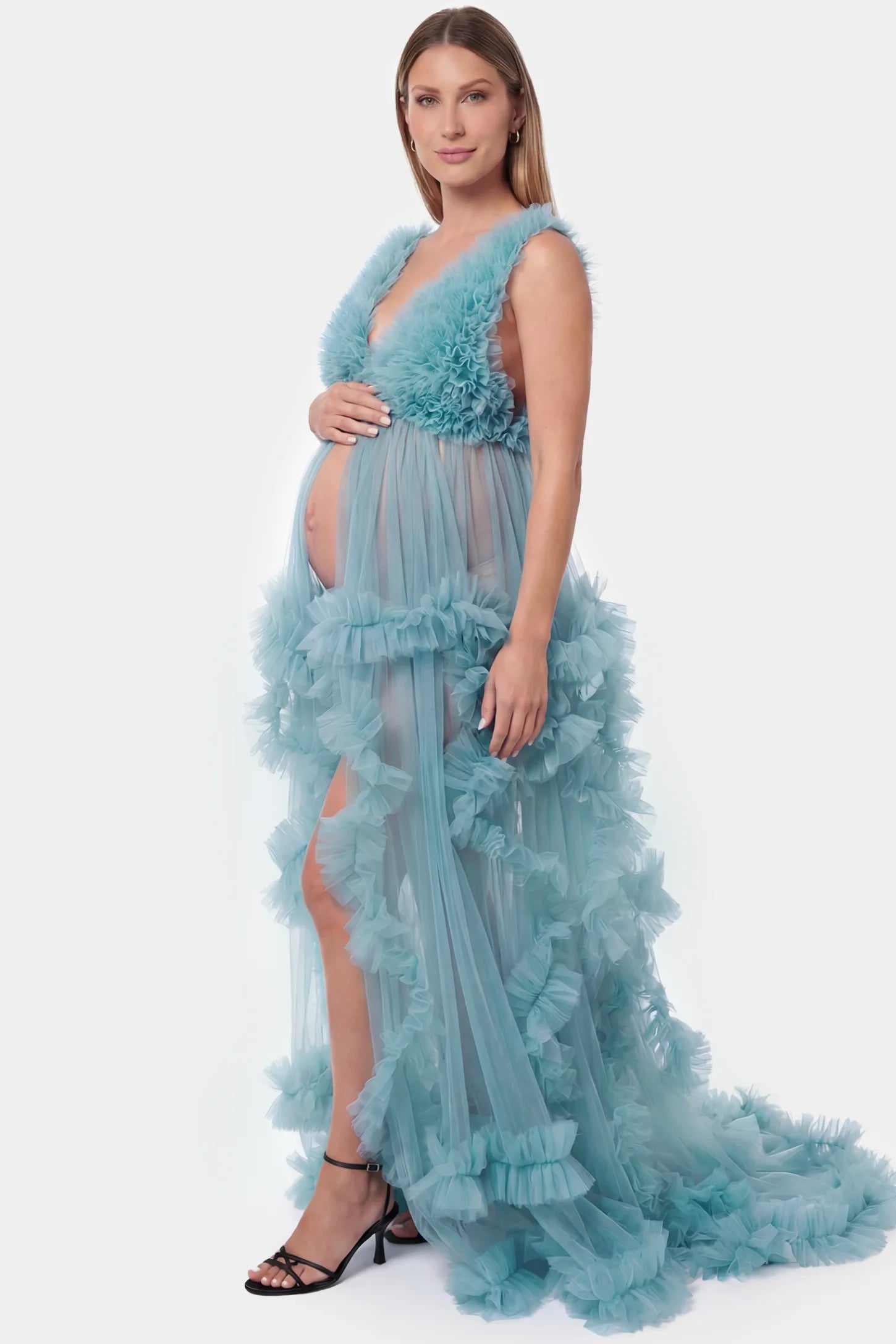 Multi-layered tulle deep V-neck sleeveless maxi maternity gown in lake blue featuring flowing pleated silhouette in full body side view on a pregnant model