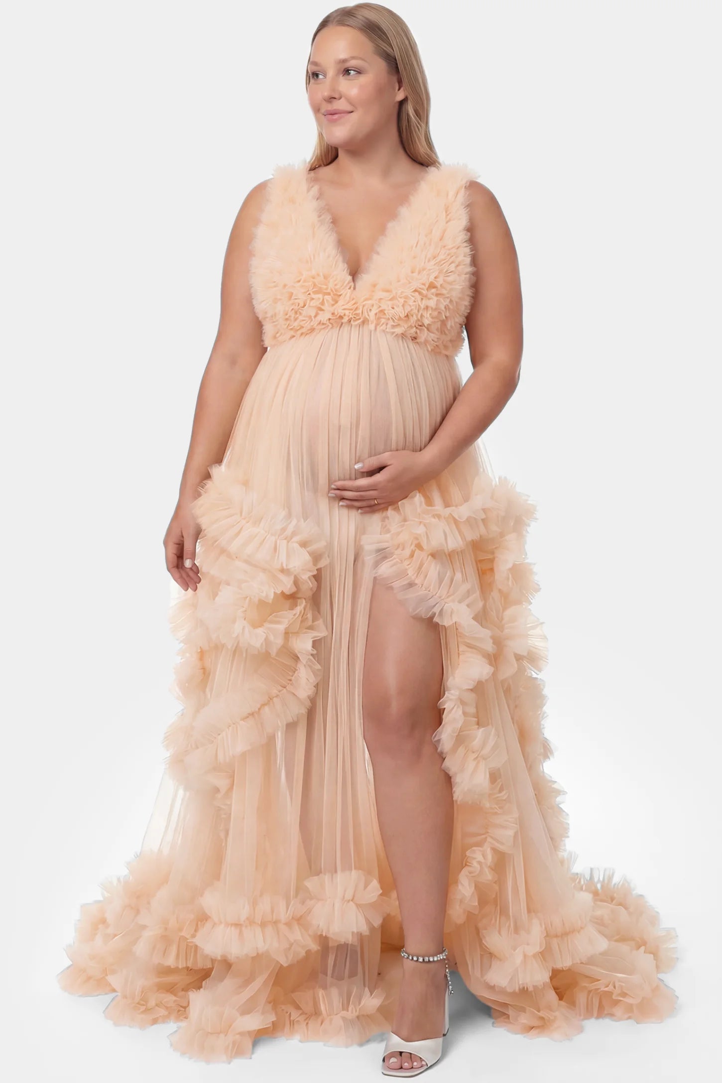 Multi-Layered Tulle Deep V-Neck Sleeveless Maxi Maternity Gown Multi-layered tulle deep V-neck sleeveless maxi maternity gown in nude featuring flowing pleated silhouette in full body front view on a plus-size model