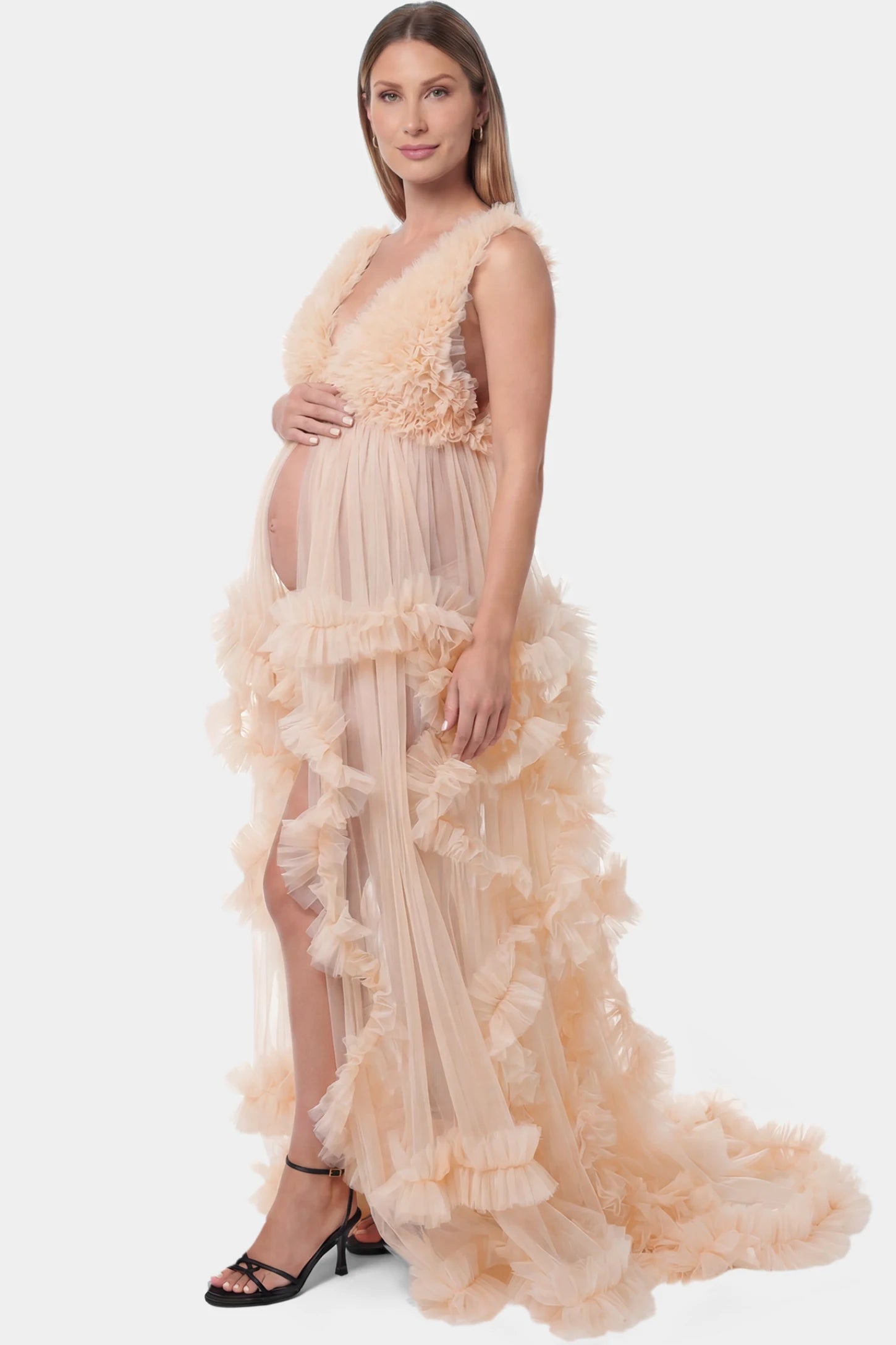 Multi-Layered Tulle Deep V-Neck Sleeveless Maxi Maternity Gown Multi-layered tulle deep V-neck sleeveless maxi maternity gown in nude featuring flowing pleated silhouette in full body side view on a pregnant model