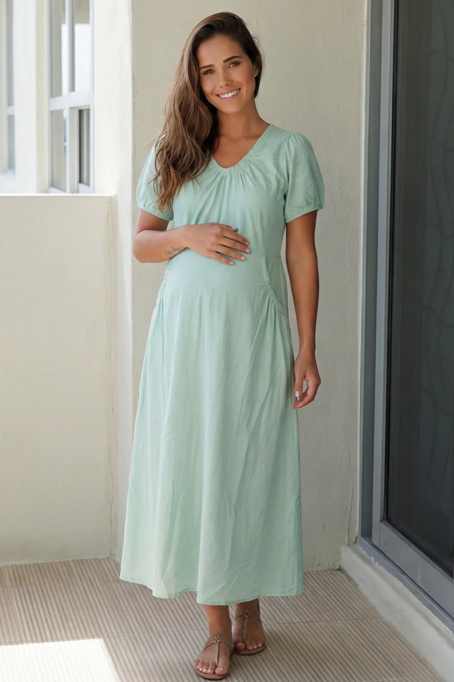 V-Neck Short Sleeve Maternity Midi Dress with Pockets V-neck short sleeve maternity midi dress with pockets in green with V-neckline detail, front view on pregnant model