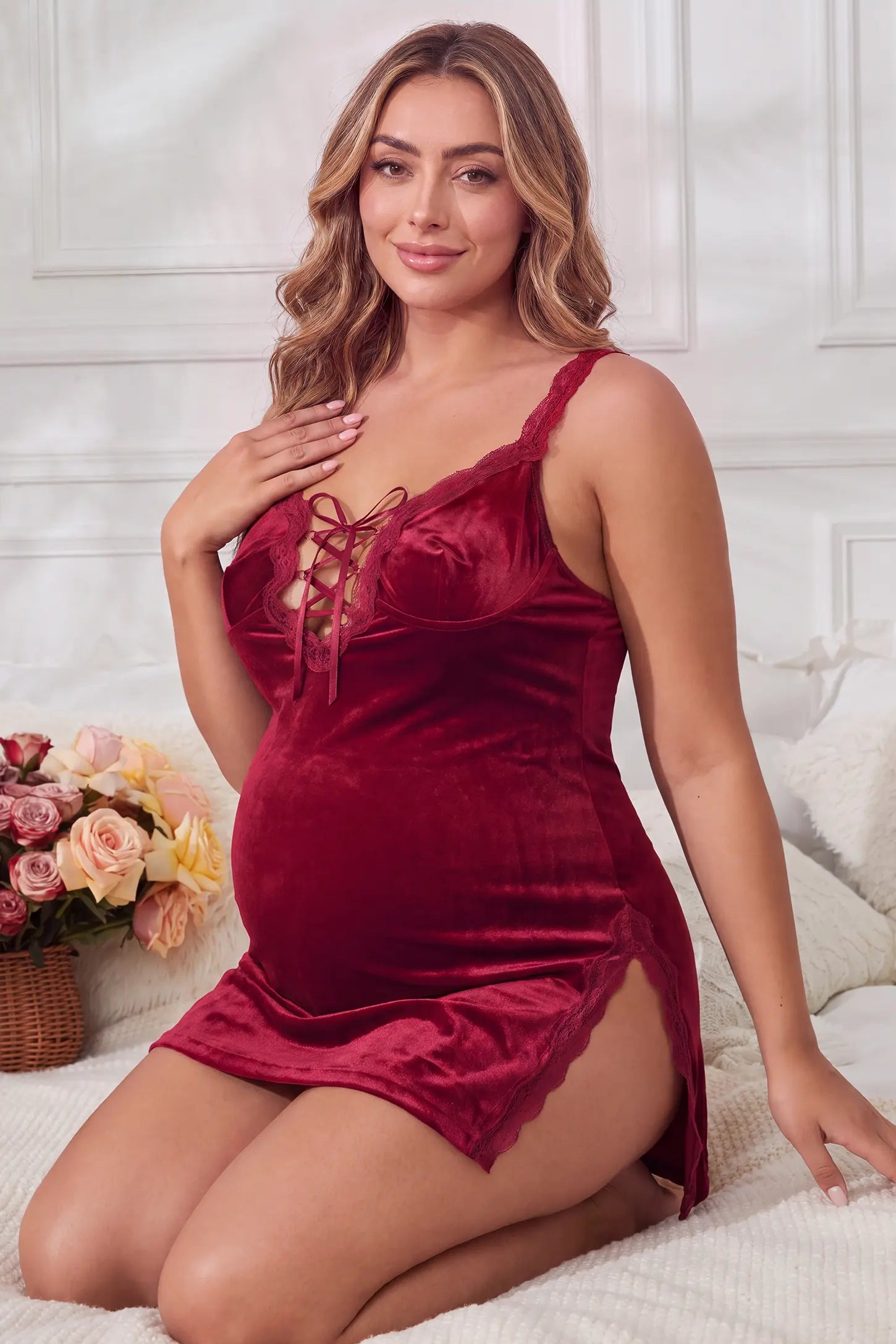 Velvet Lace Maternity Babydoll Nightgowns Velvet Lace Maternity Babydoll Nightgowns in Burgundy featuring comfortable bump coverage, side leg split, and lace-up front on a pregnant model, kneeling bed view.