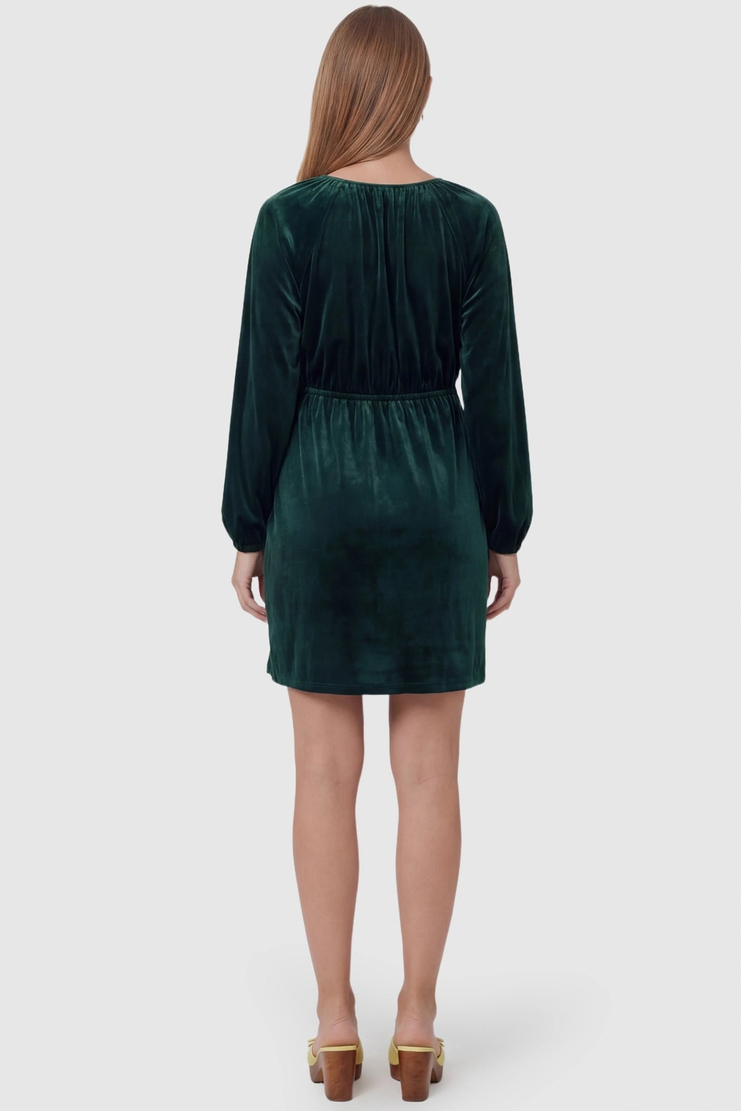 Velvet Ruched A-Line Maternity Mini Dress Velvet Ruched A-Line Maternity Mini Dress in Dark Green featuring a comfortable smocked waist on a pregnant model, back view.