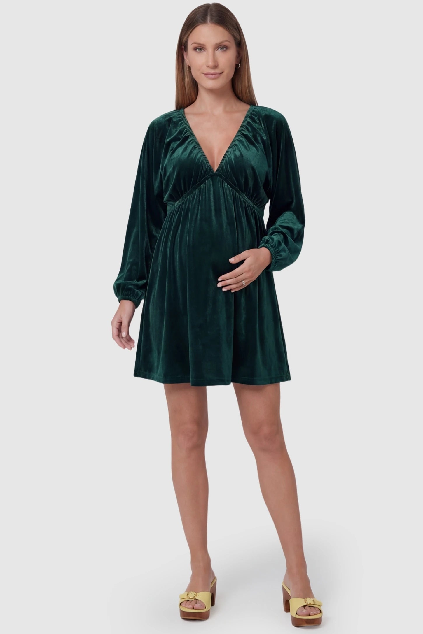 Velvet Ruched A-Line Maternity Mini Dress in Dark Green featuring a retro V-neck on a pregnant model, front view.