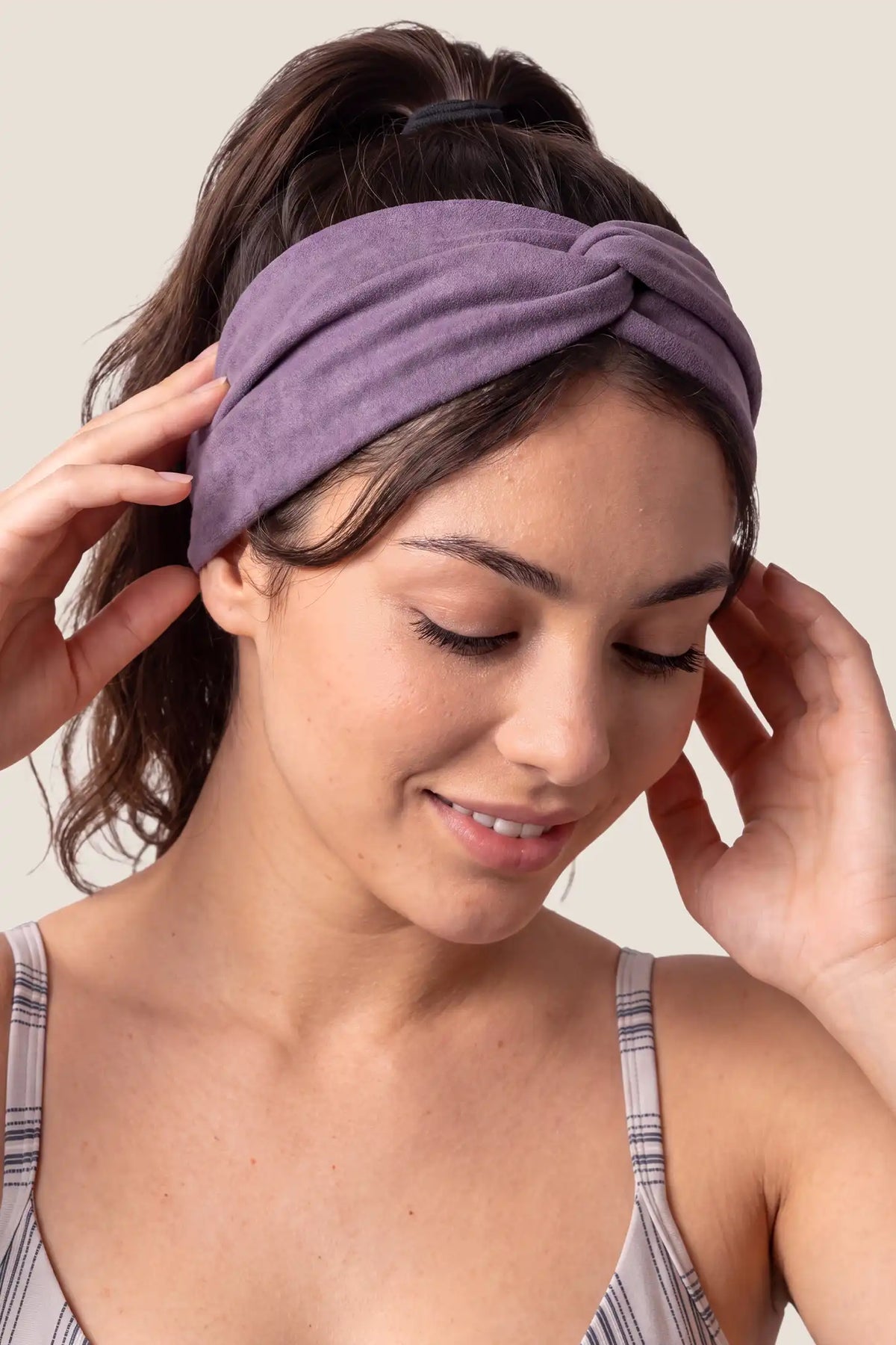 Wide Crossed Headband Wide Crossed Headband in Dusty Purple featuring a chic front knot detail and wide profile design on a woman touching her hair, close-up portrait view.