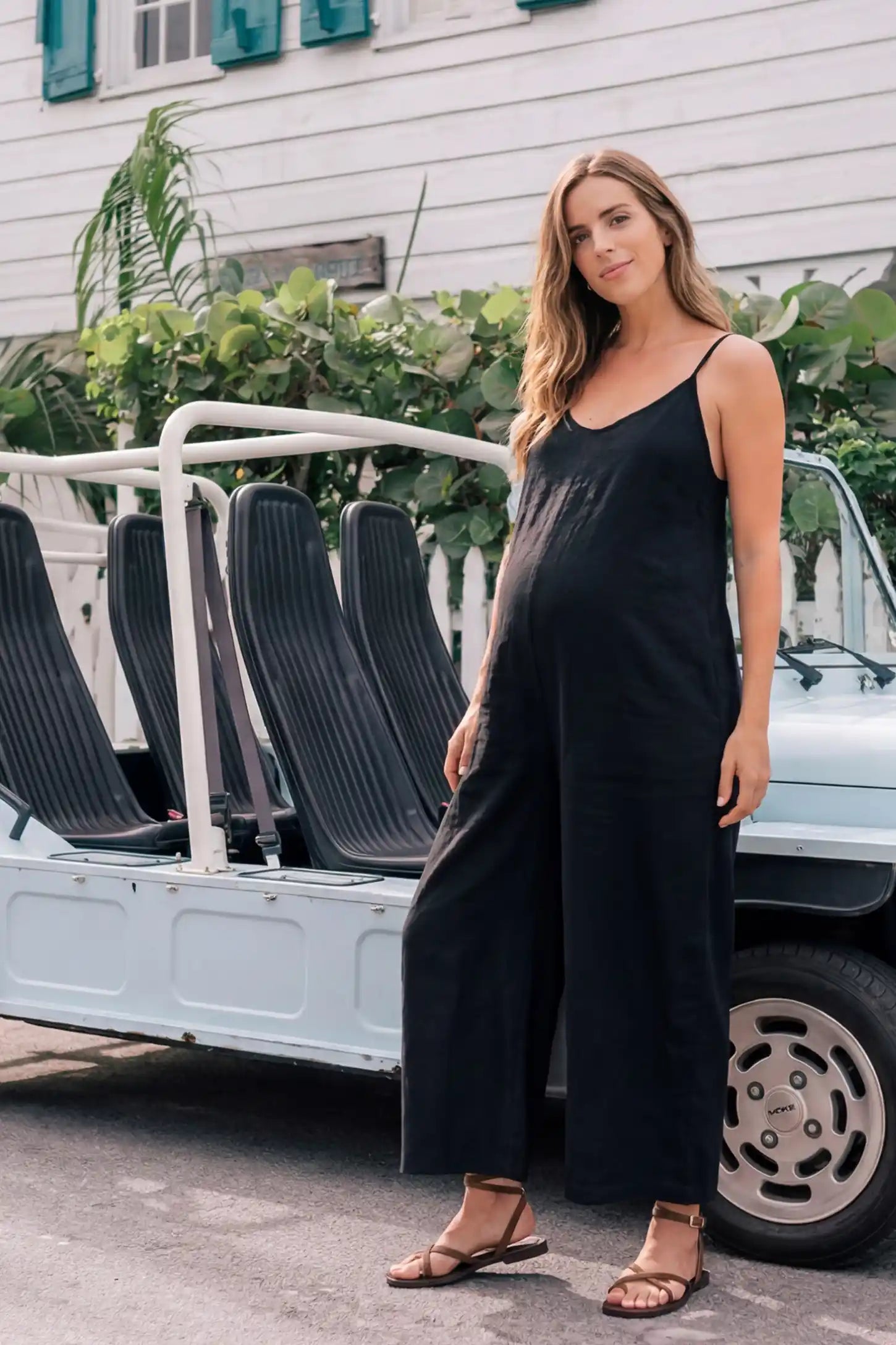 Wide‑Leg Scoop Neck Pocketed Maternity Jumpsuit Wide-leg scoop neck pocketed maternity jumpsuit in black with sleeveless design, thin strap, and wide-leg silhouette, editorial lifestyle model