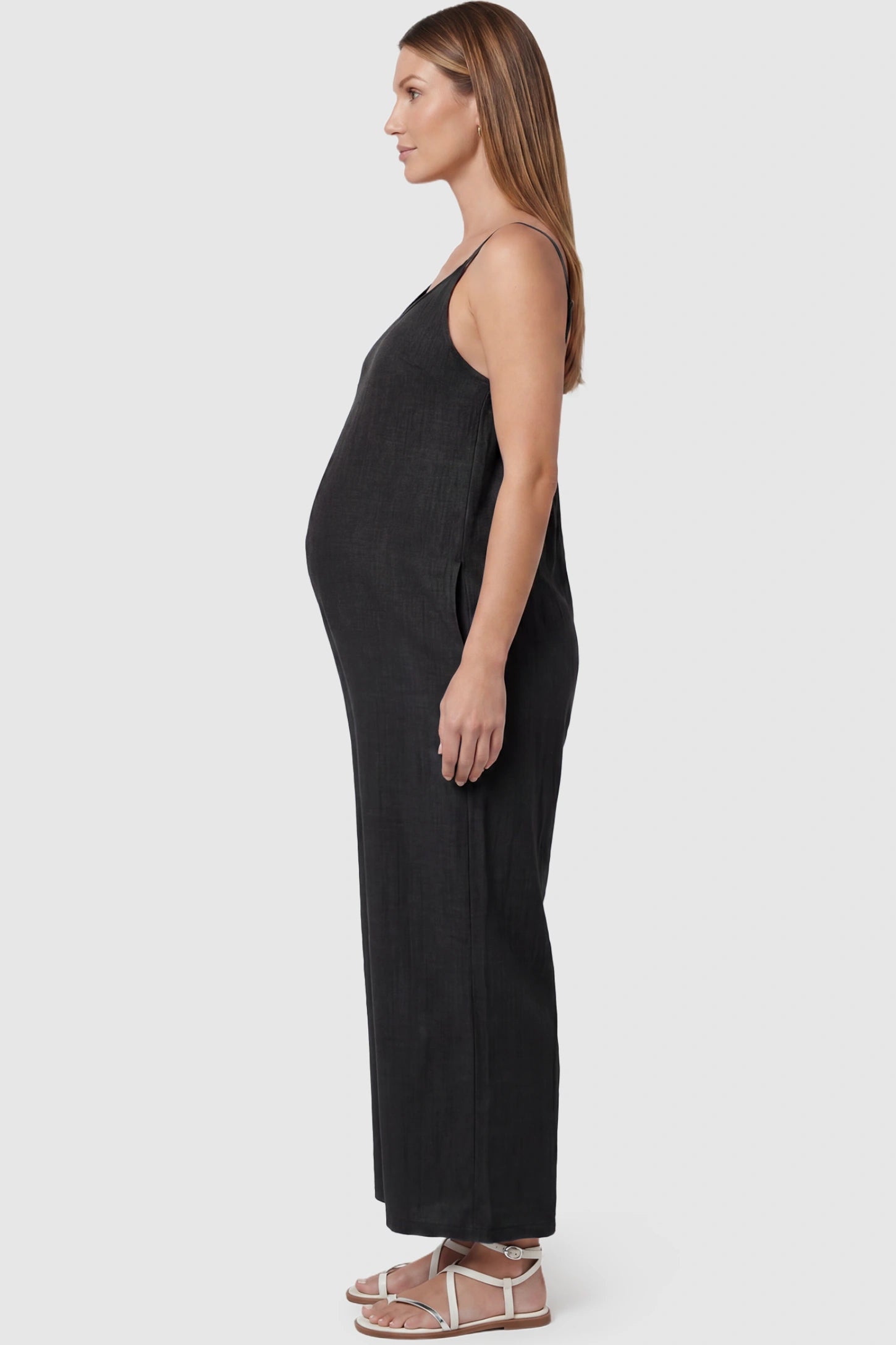 Wide‑Leg Scoop Neck Pocketed Maternity Jumpsuit Wide-leg scoop neck pocketed maternity jumpsuit in black with sleeveless design, thin strap, and wide-leg silhouette, side view on pregnant model