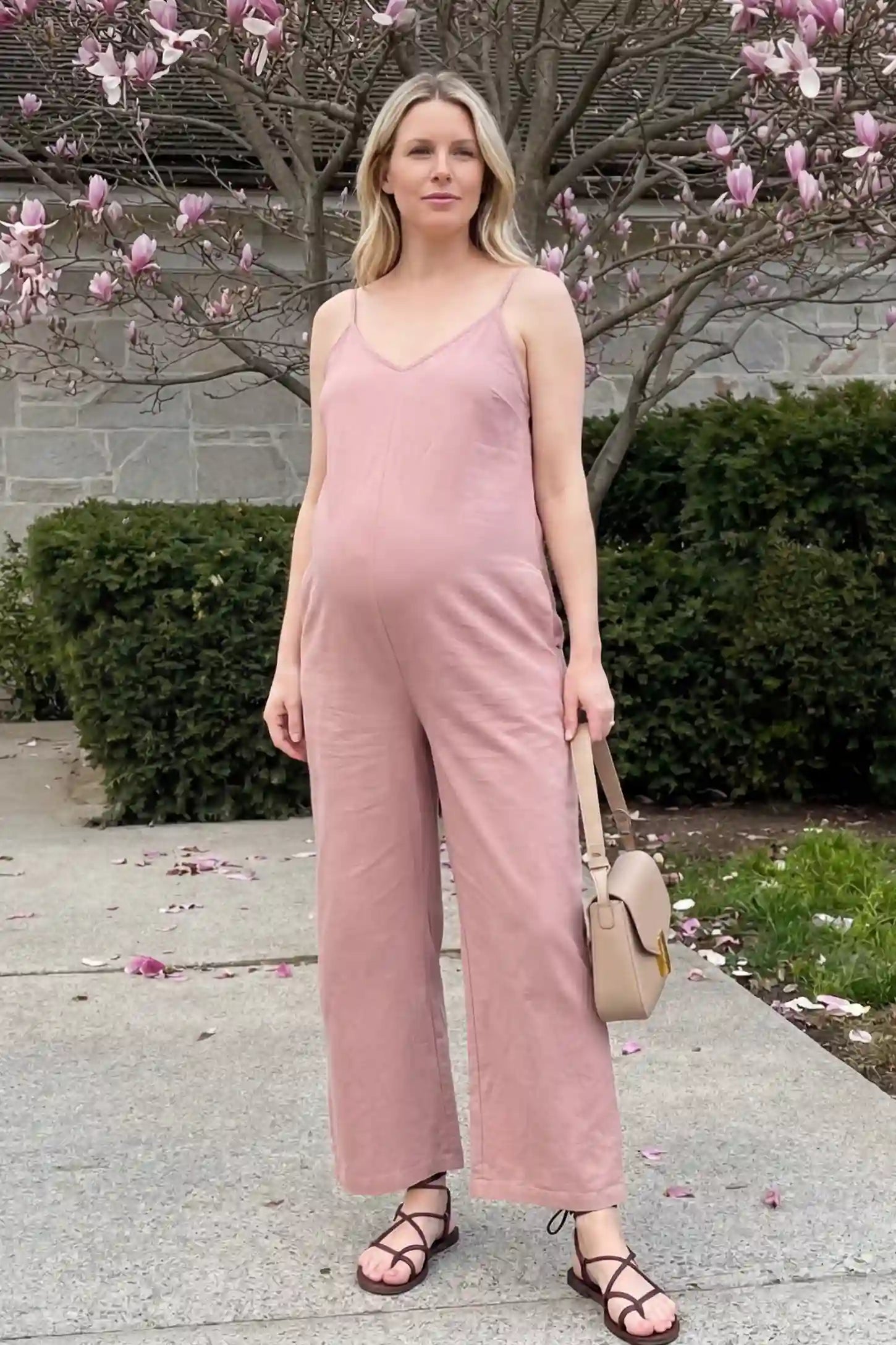 Wide‑Leg Scoop Neck Pocketed Maternity Jumpsuit Wide-leg scoop neck pocketed maternity jumpsuit in pink with sleeveless design, thin strap, and wide-leg silhouette, editorial lifestyle model