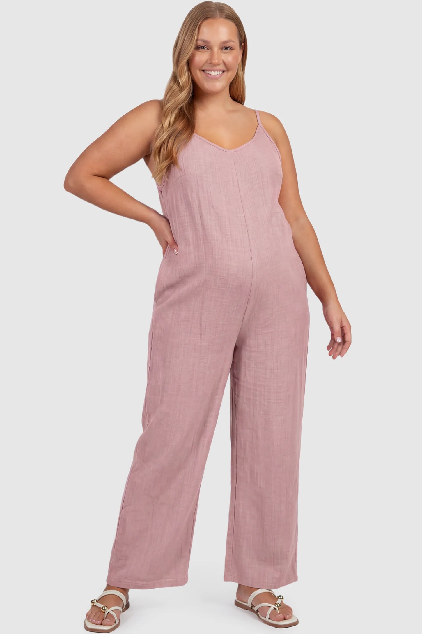 Wide‑Leg Scoop Neck Pocketed Maternity Jumpsuit Wide-leg scoop neck pocketed maternity jumpsuit in pink with sleeveless design, thin strap, and wide-leg silhouette, front view on plus-size model