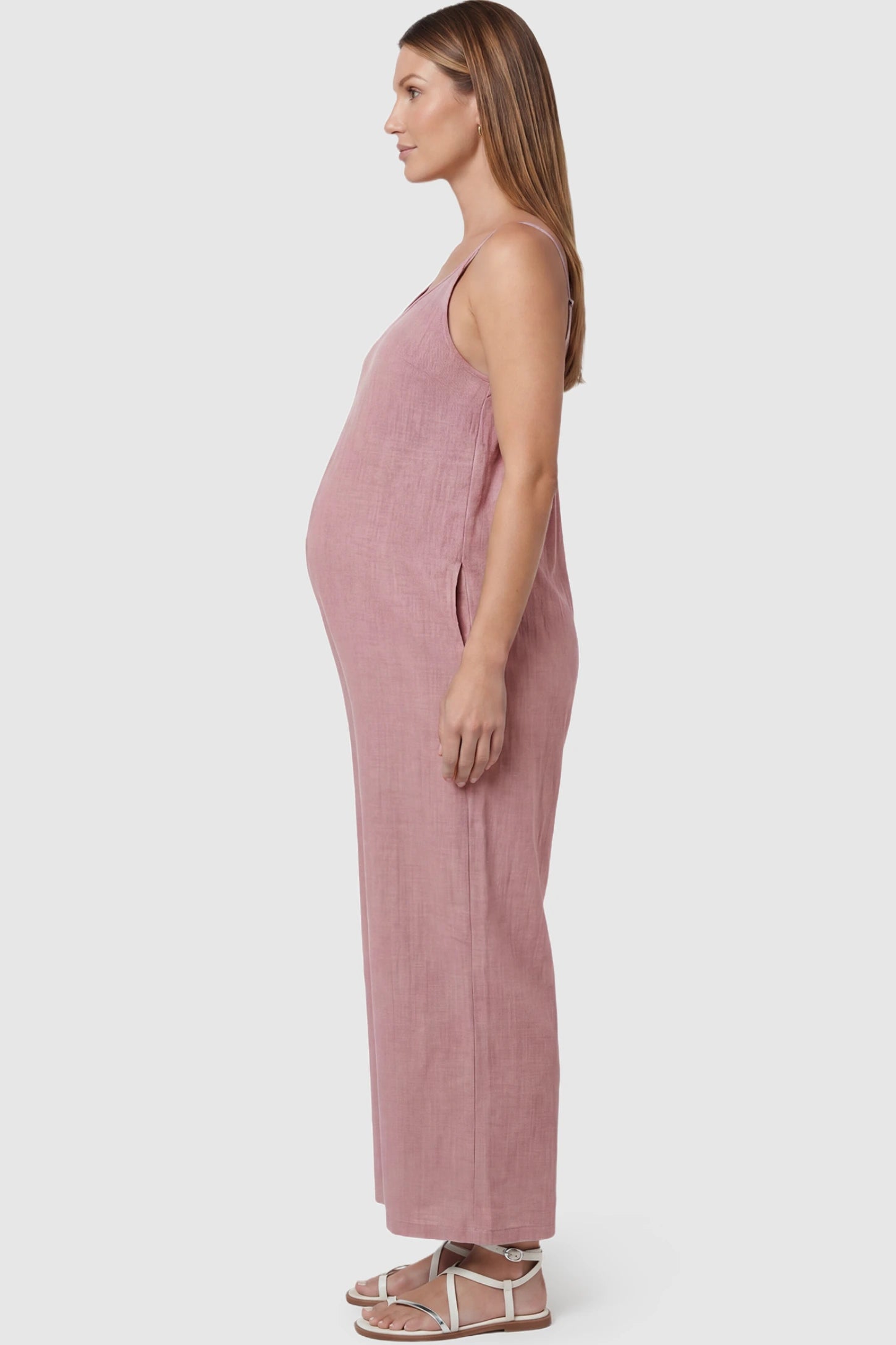 Wide‑Leg Scoop Neck Pocketed Maternity Jumpsuit Wide-leg scoop neck pocketed maternity jumpsuit in pink with sleeveless design, thin strap, and wide-leg silhouette, side view on pregnant model