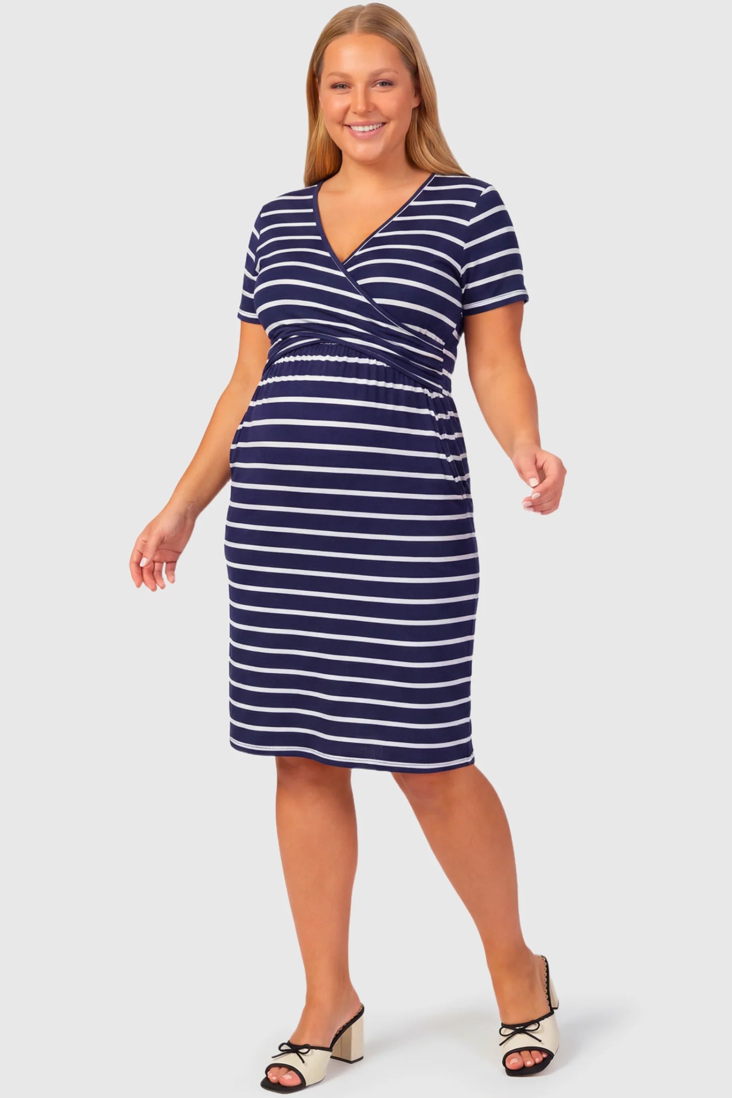 Short Sleeve Faux Wrap Maternity & Nursing Midi Dress Short Sleeve Faux Wrap Maternity & Nursing Midi Dress in navy striped print featuring V-neck faux wrap bodice and empire waist on a plus size pregnant model.