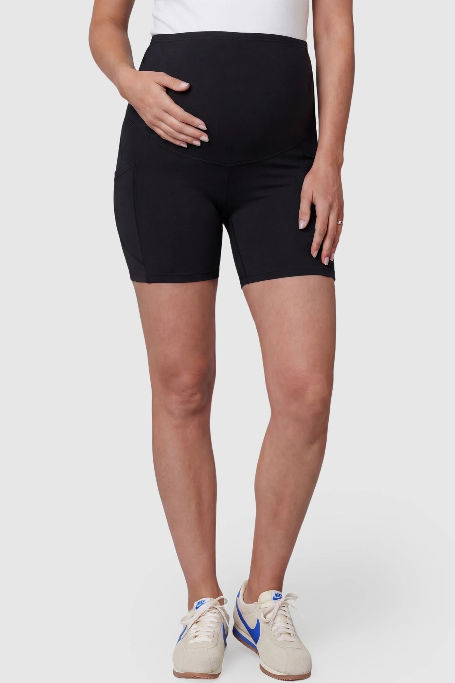 High-waist tummy support body-hugging maternity shorts in black with support waistband, front view on pregnant model