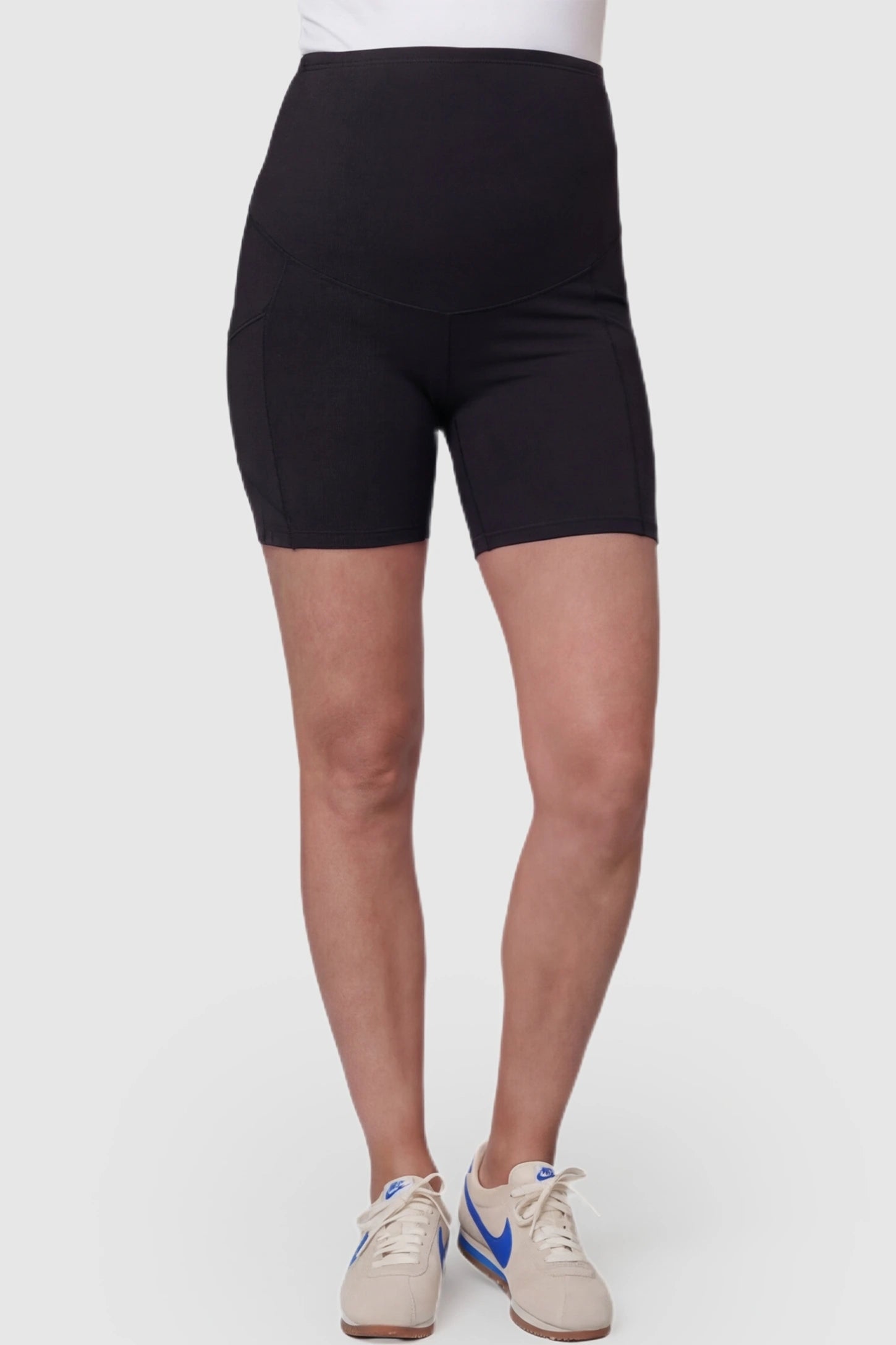 High-waist tummy support body-hugging maternity shorts in black with support waistband, front view on pregnant model