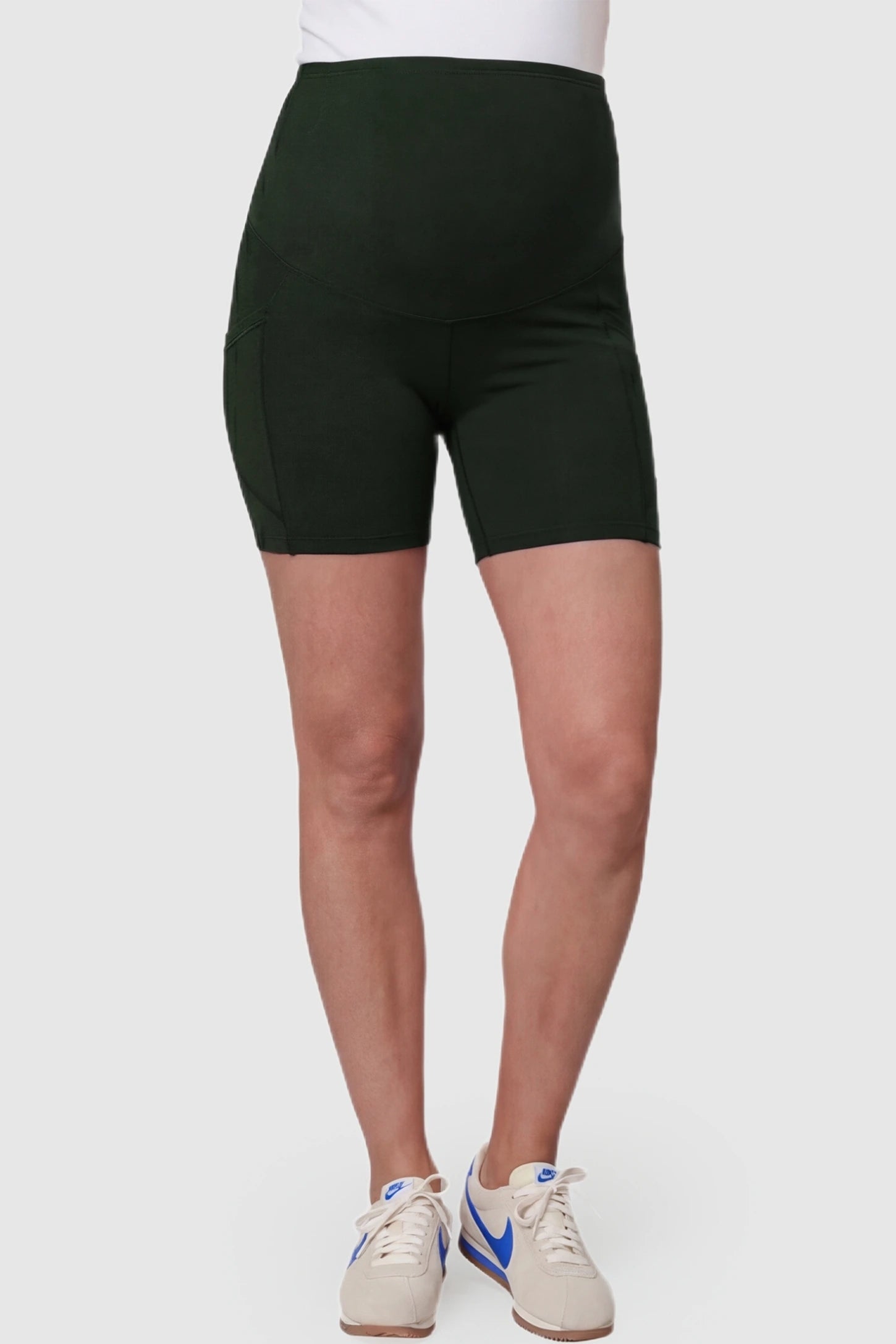 High-Waist Tummy Support Body-Hugging Maternity Shorts High-waist tummy support body-hugging maternity shorts in dark green with support waistband, front view on pregnant model