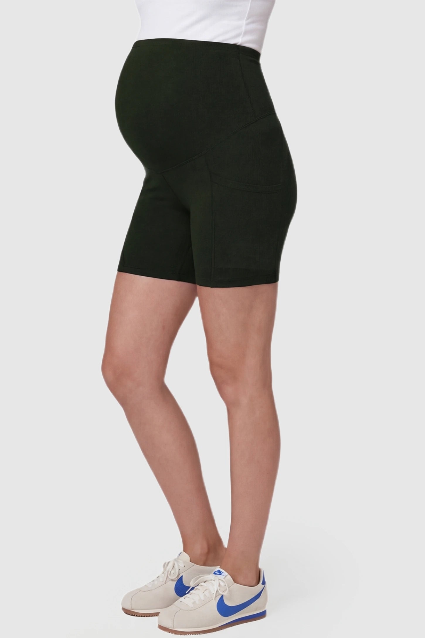 High-Waist Tummy Support Body-Hugging Maternity Shorts High-waist tummy support body-hugging maternity shorts in dark green with flexible stretch, side view on pregnant model