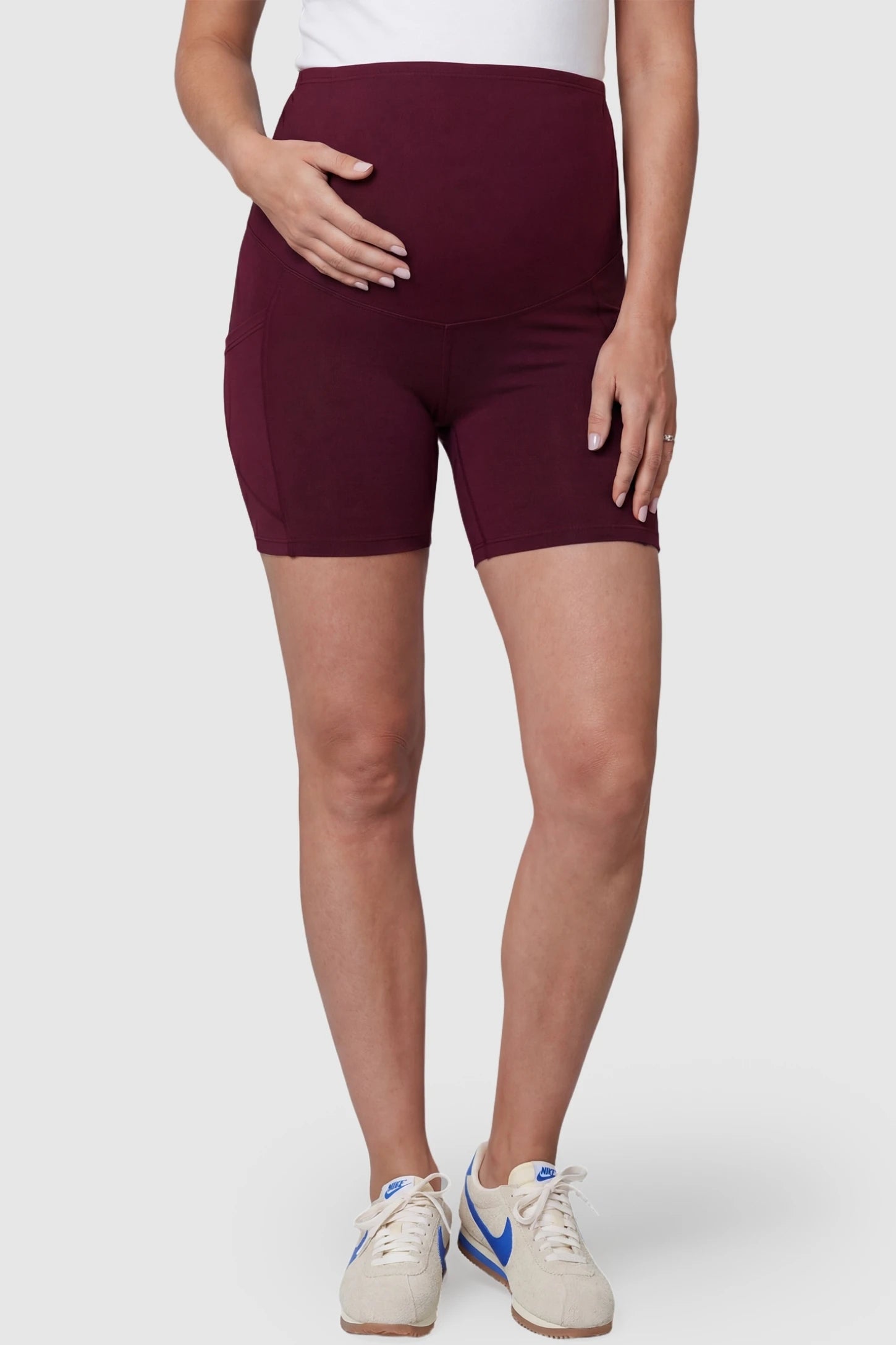 High-Waist Tummy Support Body-Hugging Maternity Shorts High-waist tummy support body-hugging maternity shorts in wine red with support waistband, front view on pregnant model