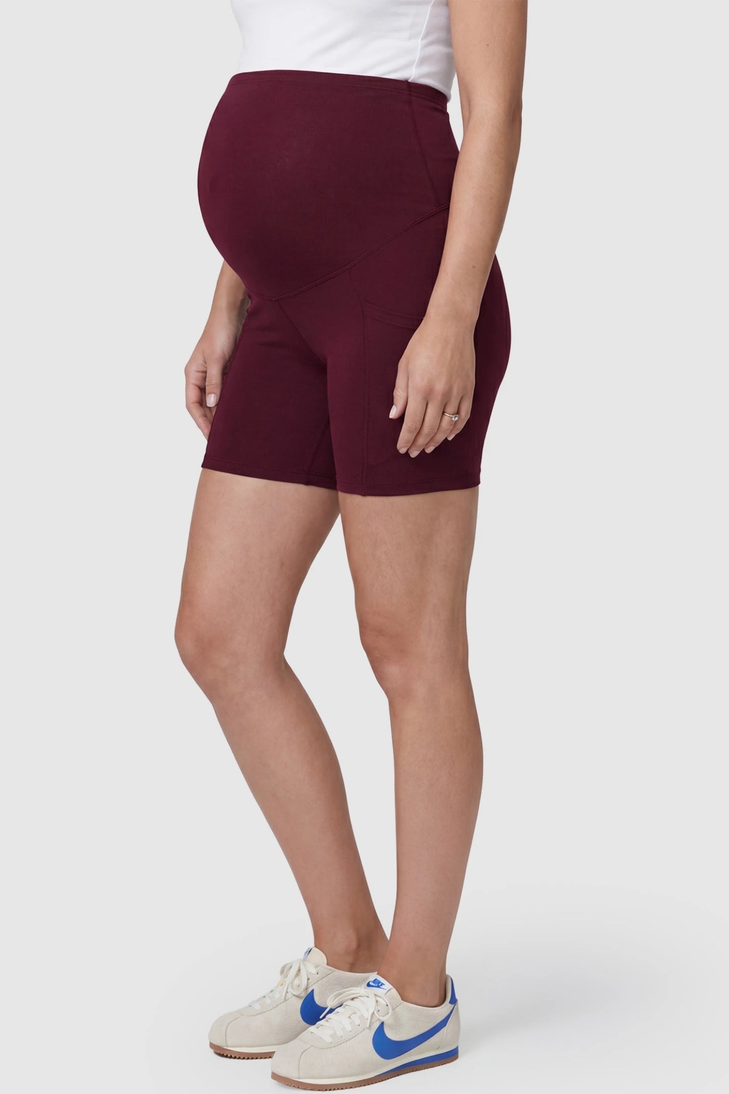 High-Waist Tummy Support Body-Hugging Maternity Shorts High-waist tummy support body-hugging maternity shorts in wine red with flexible stretch, side view on pregnant model