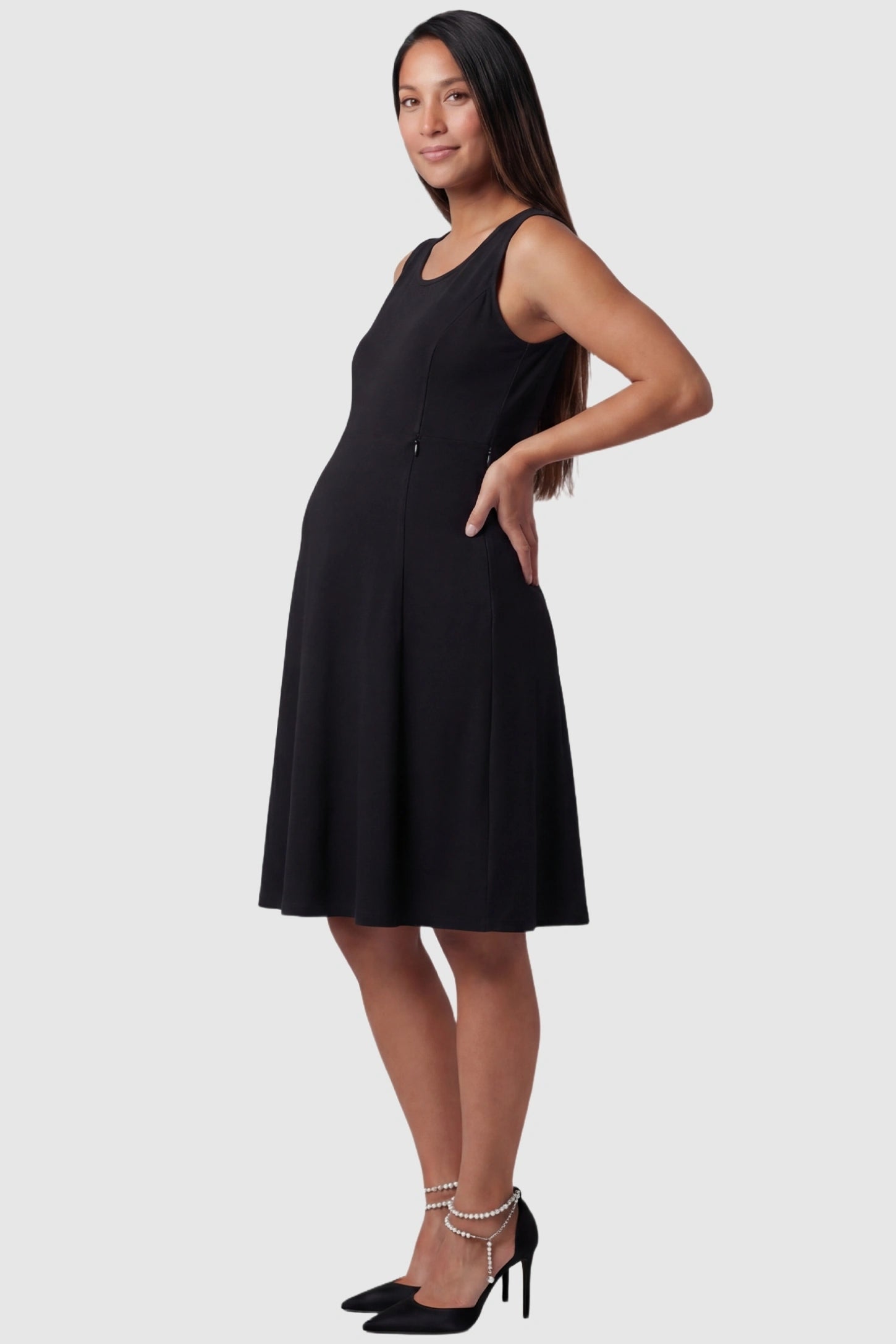 Zip-Up Nursing Access A-Line Maternity Tank Dress in Black featuring hidden side zippers for nursing on a pregnant model, side view.