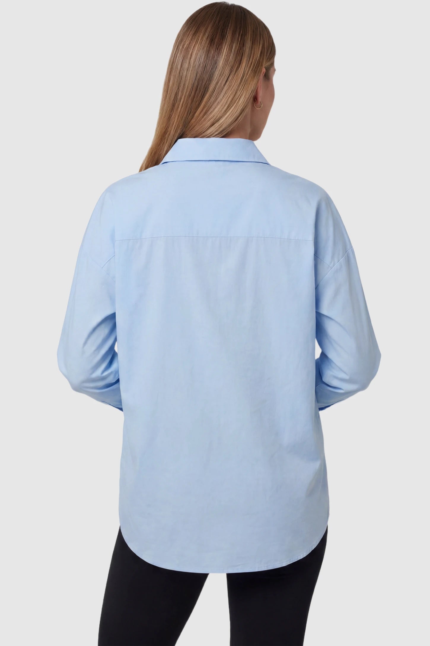 Button Down Collared Maternity Shirt Button Down Collared Maternity Shirt in light blue featuring long sleeves and a crisp cotton finish on a pregnant model, back view.
