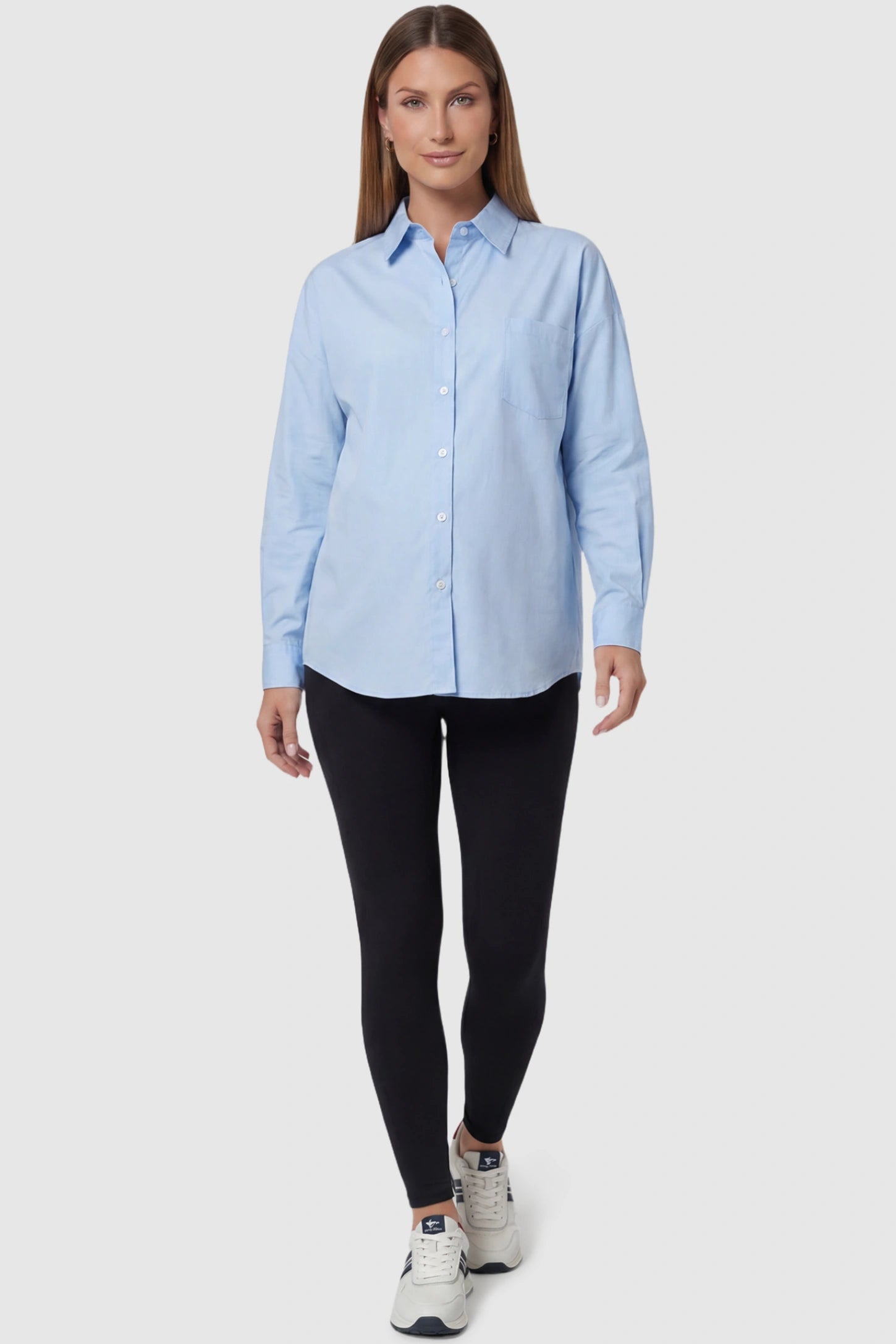 Button Down Collared Maternity Shirt Button Down Collared Maternity Shirt in light blue featuring long sleeves and a crisp cotton finish on a pregnant model, full body view.