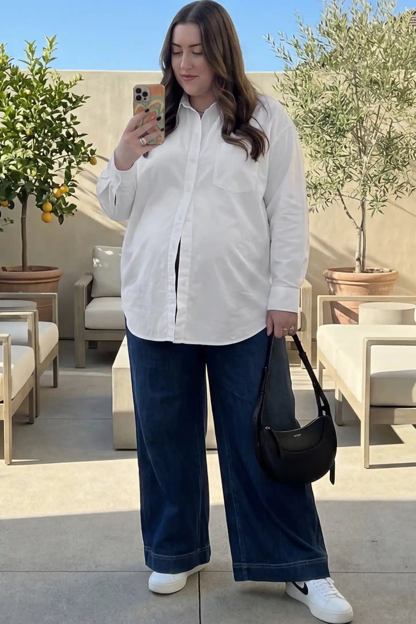 Button Down Collared Maternity Shirt Button Down Collared Maternity Shirt in white featuring long sleeves and a crisp cotton finish on a pregnant woman.