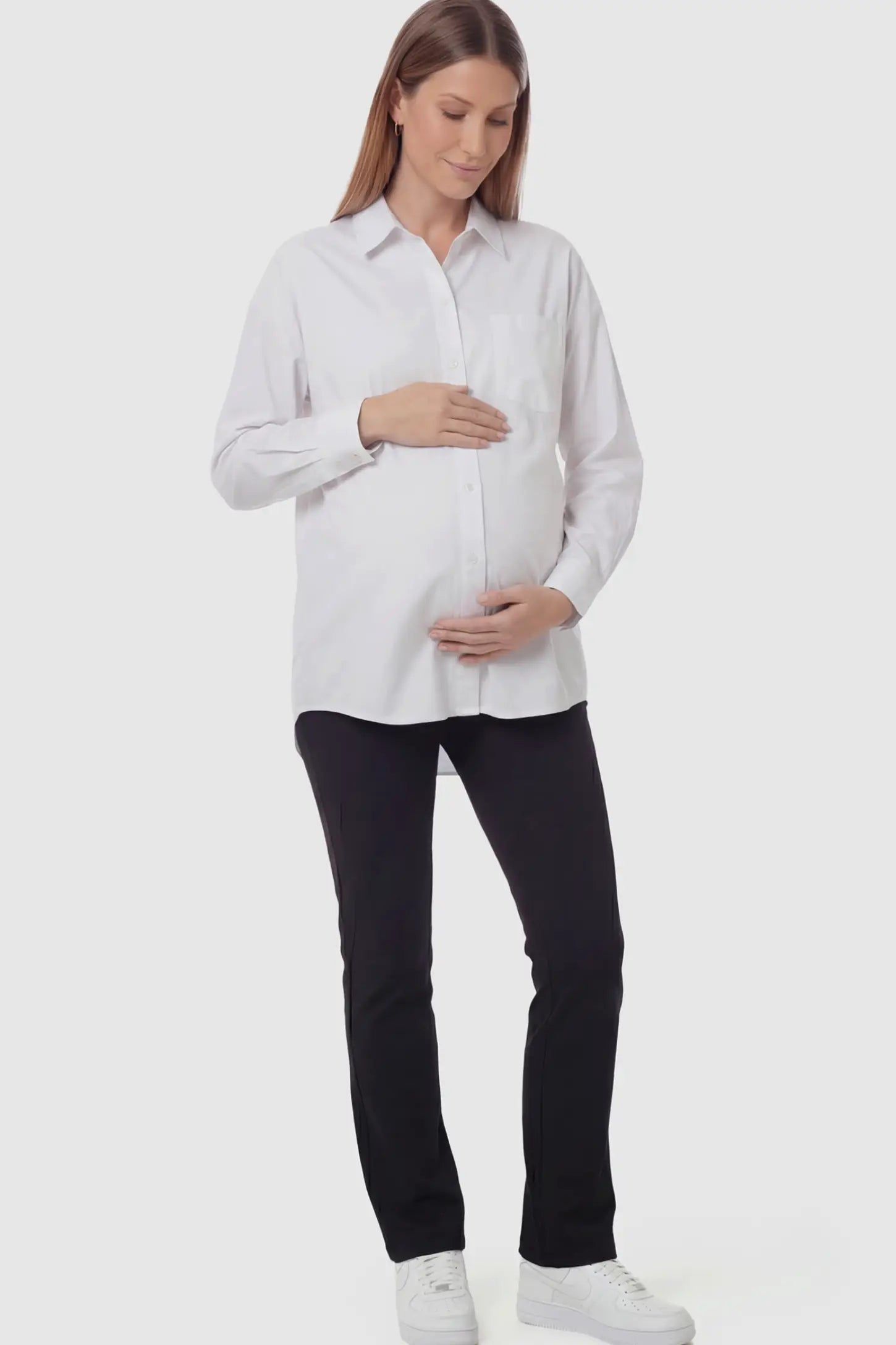 Button Down Collared Maternity Shirt Button Down Collared Maternity Shirt in white featuring long sleeves and a crisp cotton finish on a pregnant model.