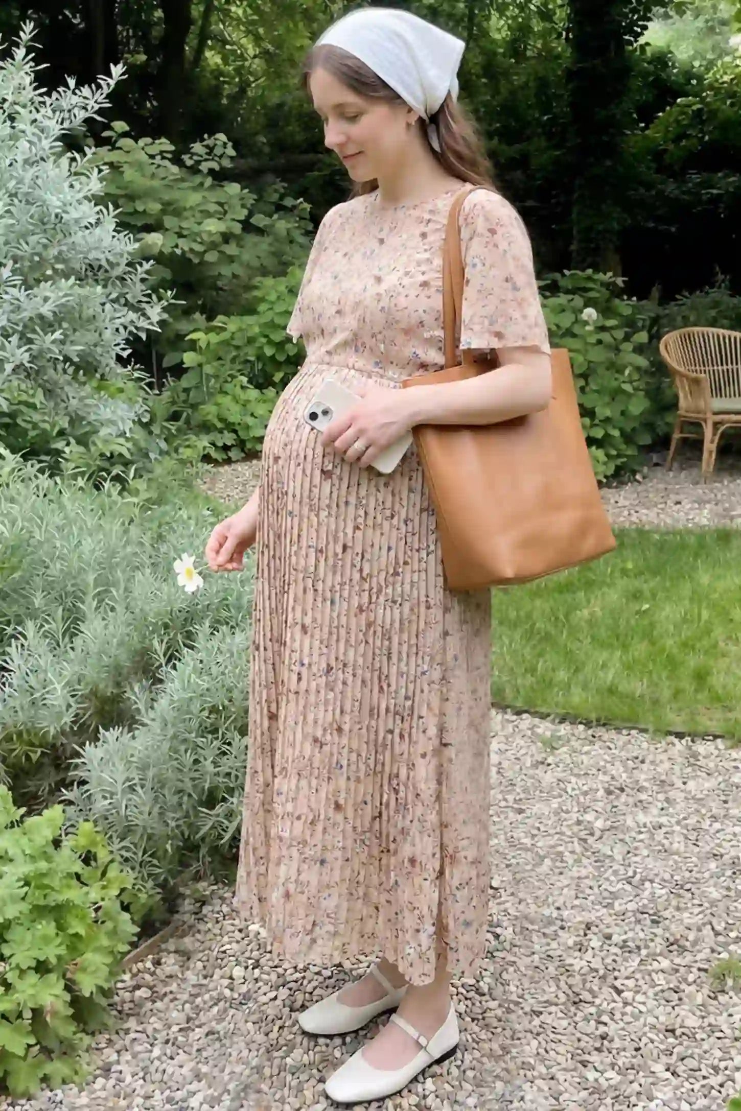Floral Print Round Neck Pleated Maternity Midi Dress Floral Print Round Neck Pleated Maternity Midi Dress in Beige Floral Print featuring a pleated A-line skirt on a pregnant woman in outdoor setting , side view.