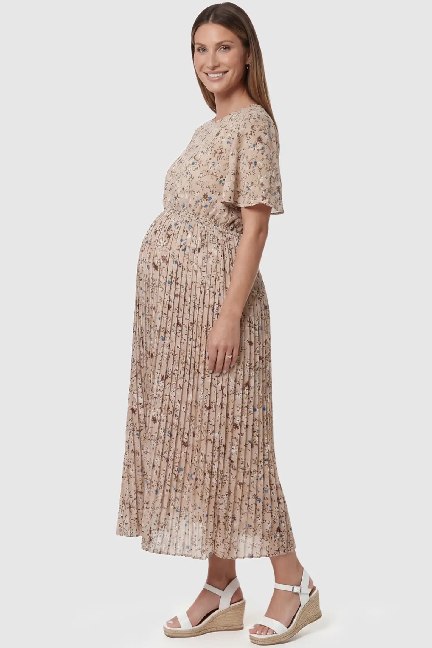 Floral Print Round Neck Pleated Maternity Midi Dress Floral Print Round Neck Pleated Maternity Midi Dress in Beige Floral Print featuring a pleated A-line skirt on a pregnant model, side view.