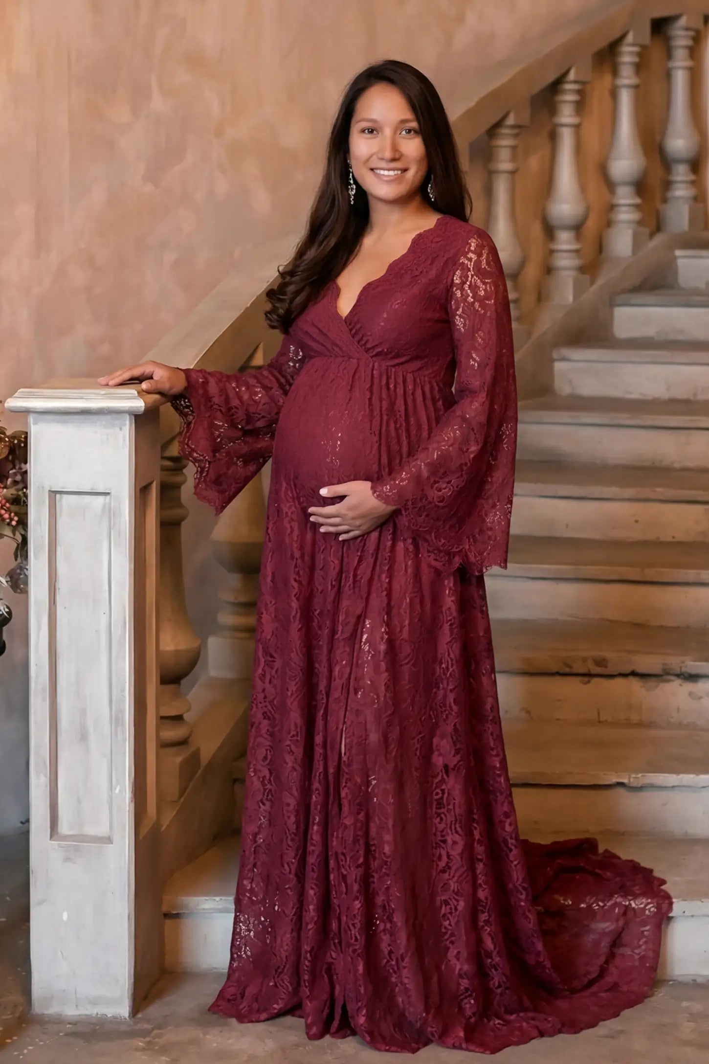 Lace Flare Long Sleeve Maternity Photoshoot Gown Lace Flare Long Sleeve Maternity Photoshoot Gown in Burgundy featuring dramatic bell sleeves on a pregnant model.