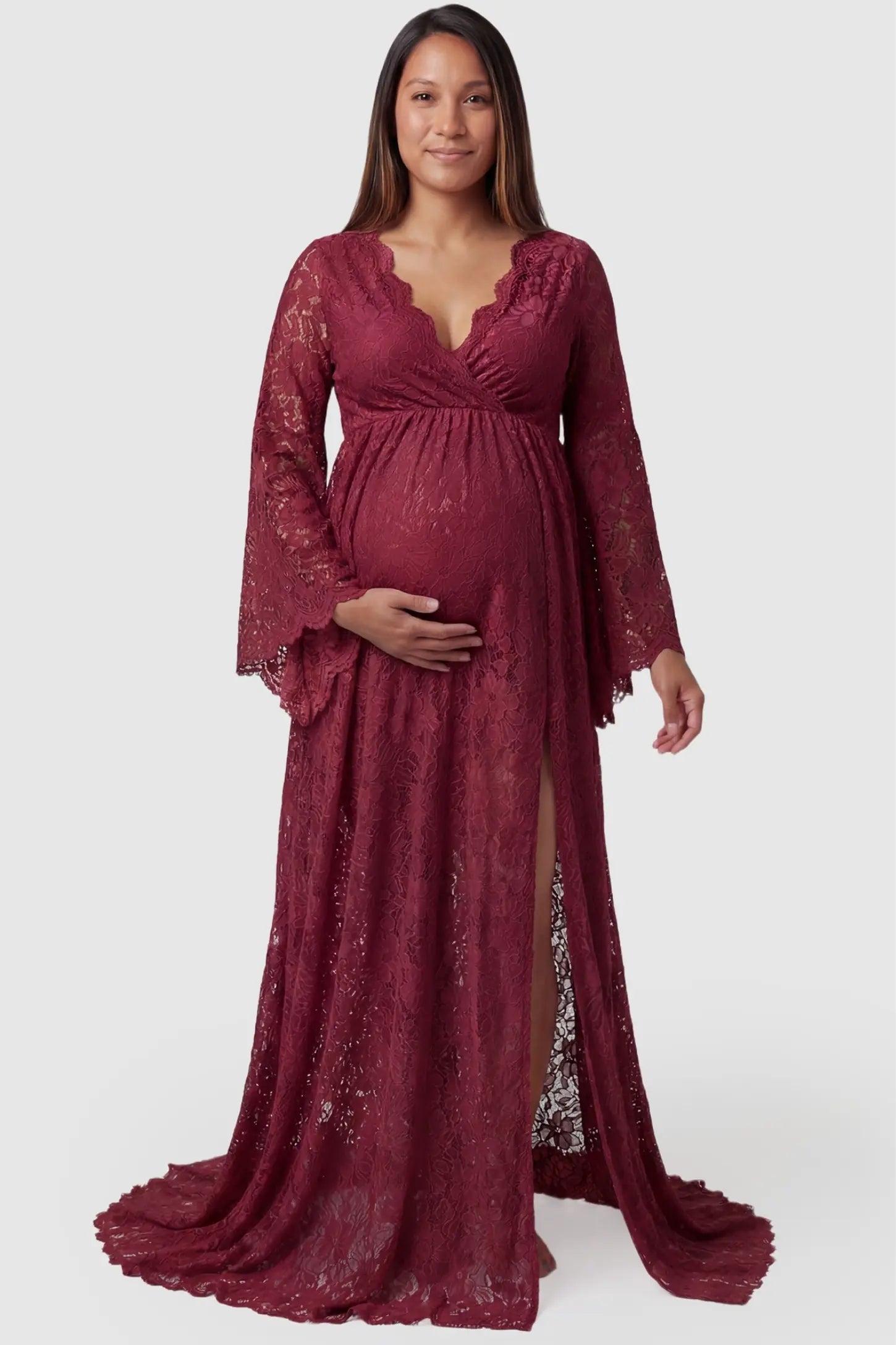 Lace Flare Long Sleeve Maternity Photoshoot Gown Front view of the Lace Flare Long Sleeve Maternity Photoshoot Gown in Burgundy featuring a front slit on a pregnant model.