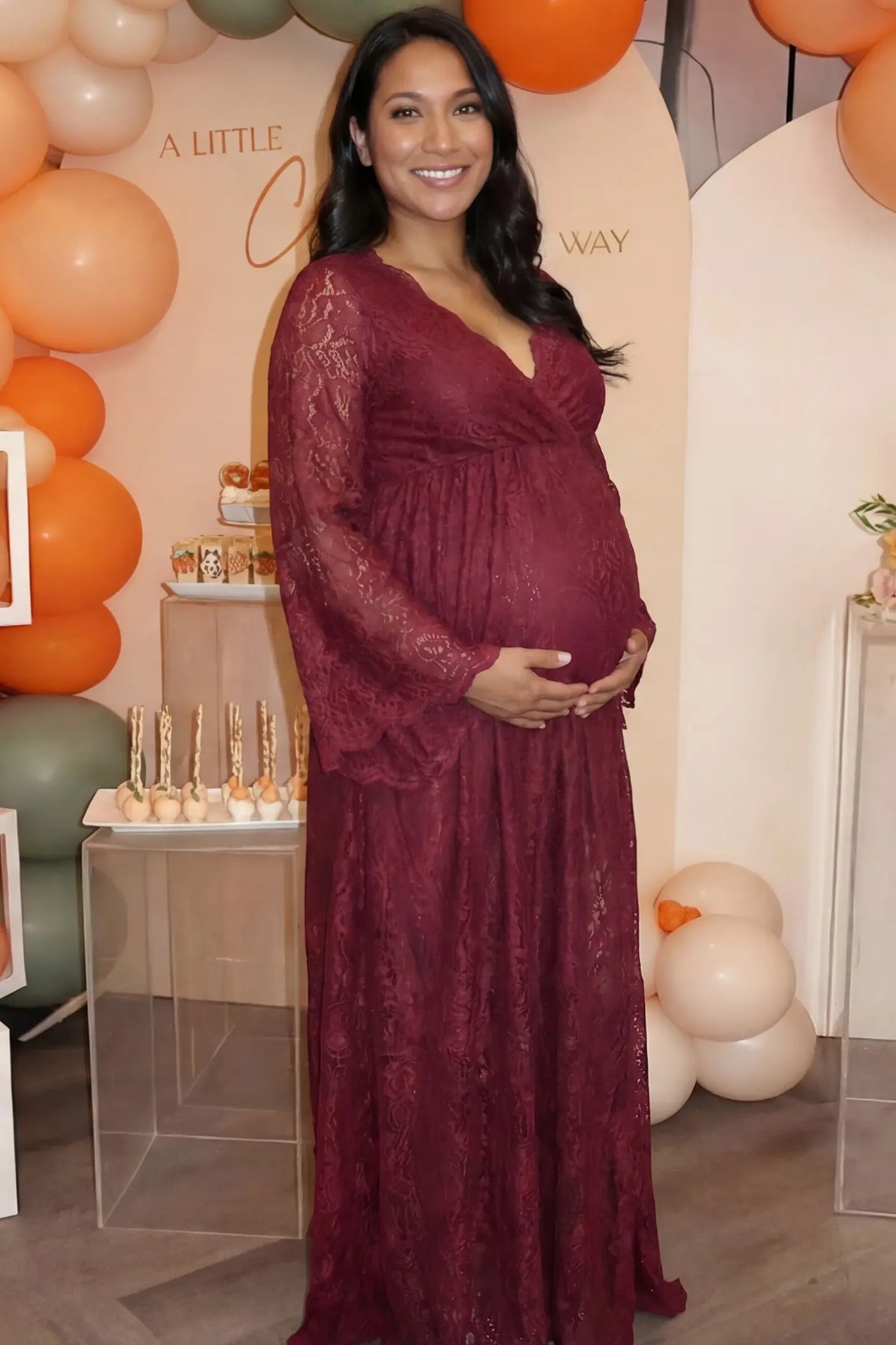 Lace Flare Long Sleeve Maternity Photoshoot Gown Lace Flare Long Sleeve Maternity Photoshoot Gown in Burgundy featuring dramatic bell sleeves on a pregnant model.