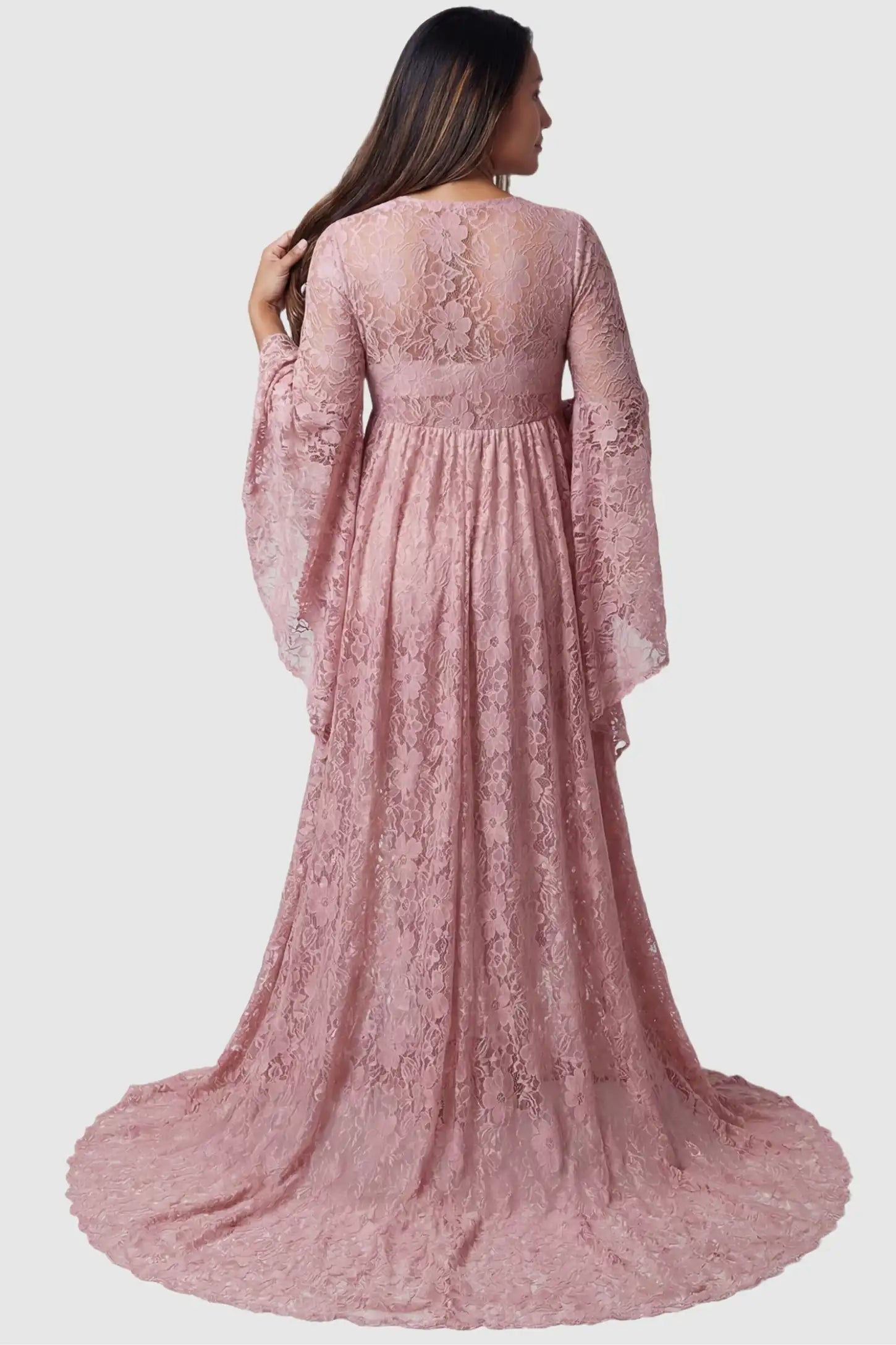 Lace Flare Long Sleeve Maternity Photoshoot Gown Back view of the Lace Flare Long Sleeve Maternity Photoshoot Gown in Light Pink featuring a sheer lace back on a pregnant model.