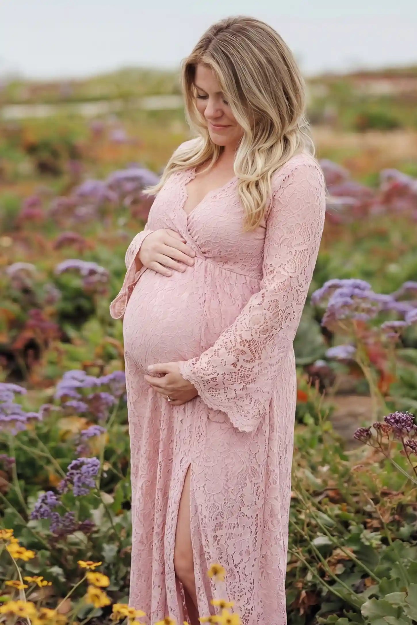 Lace Flare Long Sleeve Maternity Photoshoot Gown Lace Flare Long Sleeve Maternity Photoshoot Gown in Light Pink featuring a high-waisted empire fit on a pregnant model.