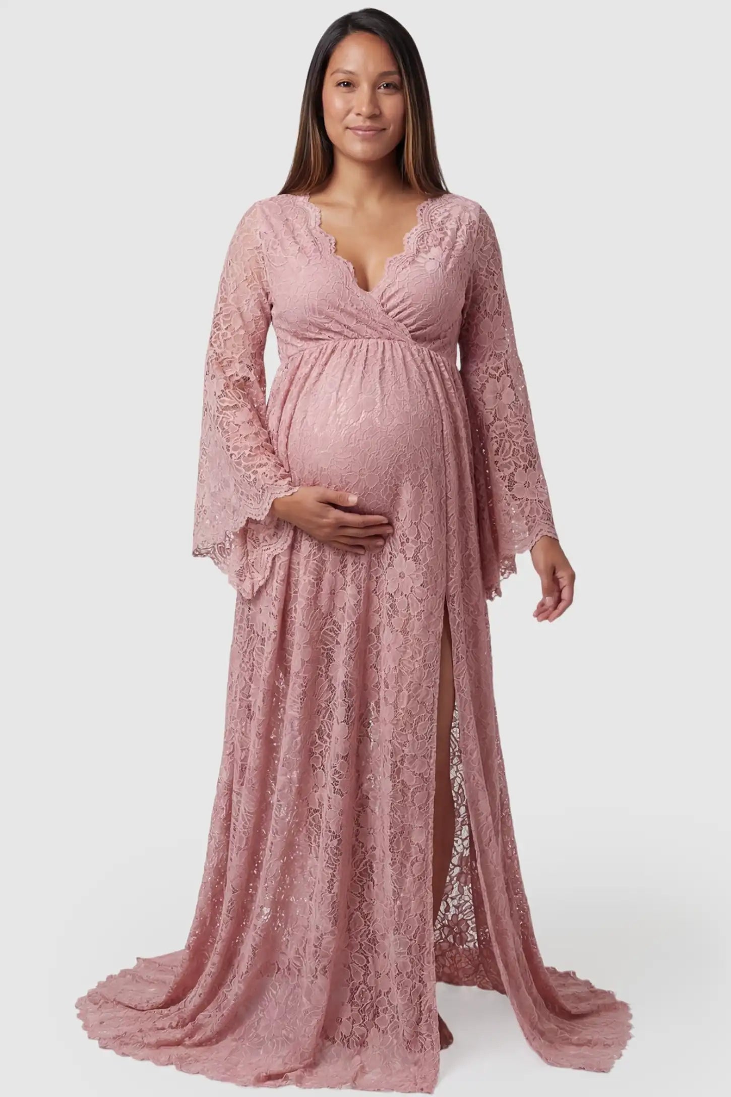 Lace Flare Long Sleeve Maternity Photoshoot Gown Front view of the Lace Flare Long Sleeve Maternity Photoshoot Gown in Light Pink featuring a surplice V-neckline on a pregnant model.