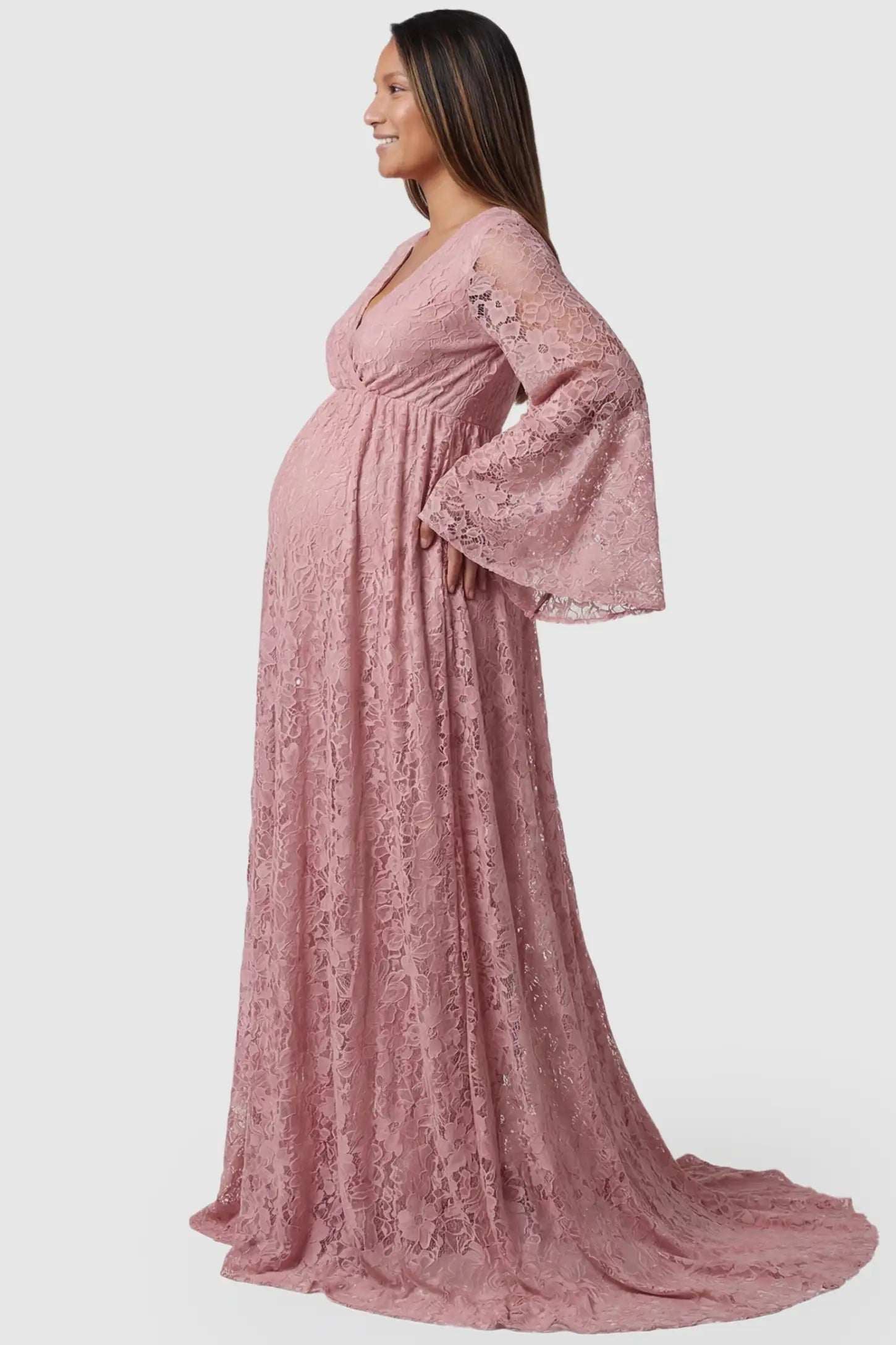 Lace Flare Long Sleeve Maternity Photoshoot Gown Side view of the Lace Flare Long Sleeve Maternity Photoshoot Gown in Light Pink featuring a high-waisted empire fit on a pregnant model.