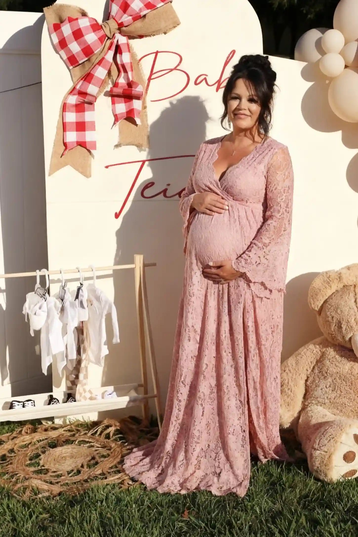 Lace Flare Long Sleeve Maternity Photoshoot Gown Lace Flare Long Sleeve Maternity Photoshoot Gown in Light Pink featuring a high-waisted empire fit on a pregnant model.
