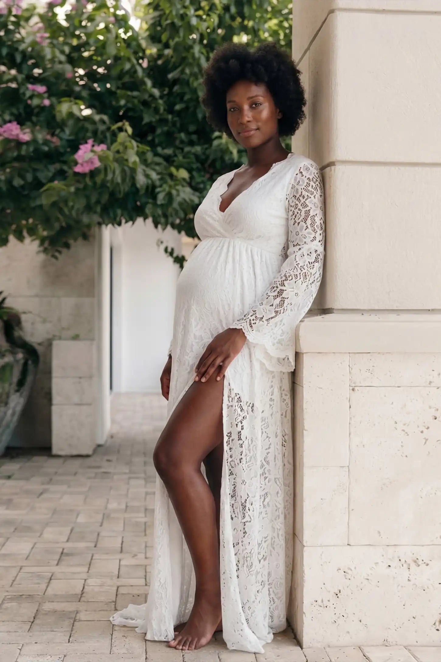 Lace Flare Long Sleeve Maternity Photoshoot Gown Lace Flare Long Sleeve Maternity Photoshoot Gown in White featuring floor-length flared sleeves on a pregnant model.