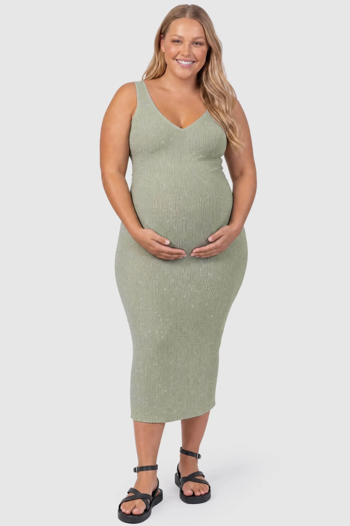 Lurex Shimmer V-Neck Sleeveless Maternity Midi Dress Lurex Shimmer V-Neck Maternity Midi Dress in beige featuring a high-stretch glitter knit on a plus size pregnant model, front view.