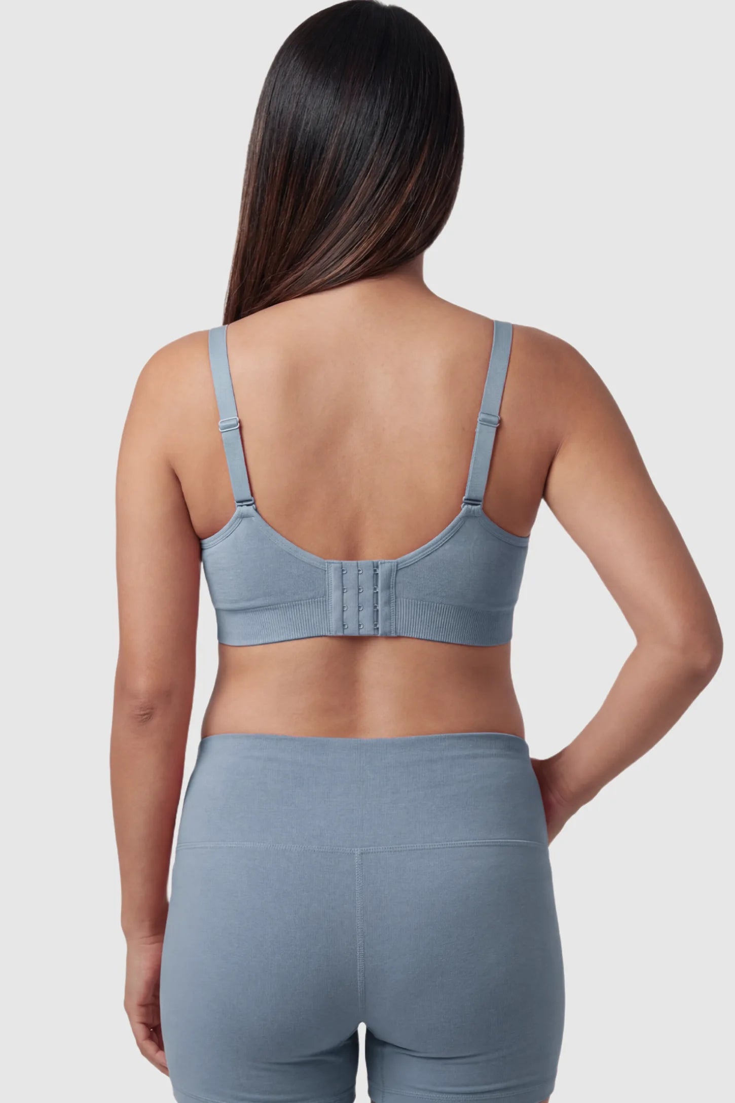Seamless Ruched Front Maternity Nursing Bra Seamless Ruched Front Maternity Nursing Bra in gray featuring ribbed fabric, adjustable straps, and a multi-hook back closure on a pregnant model from behind.
